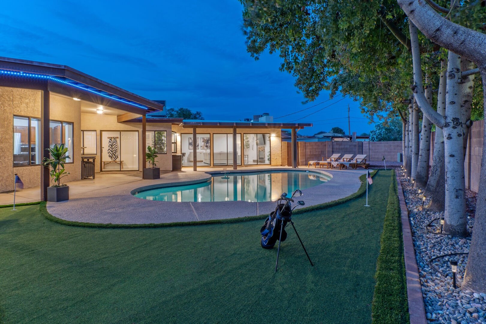 Backyard pool and putting green at dusk with golf bag