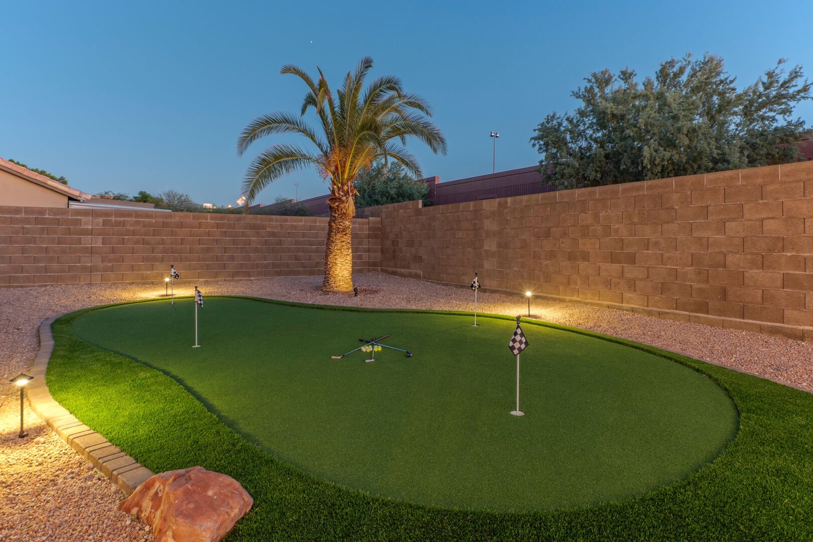 Private putting green with palm tree at dusk