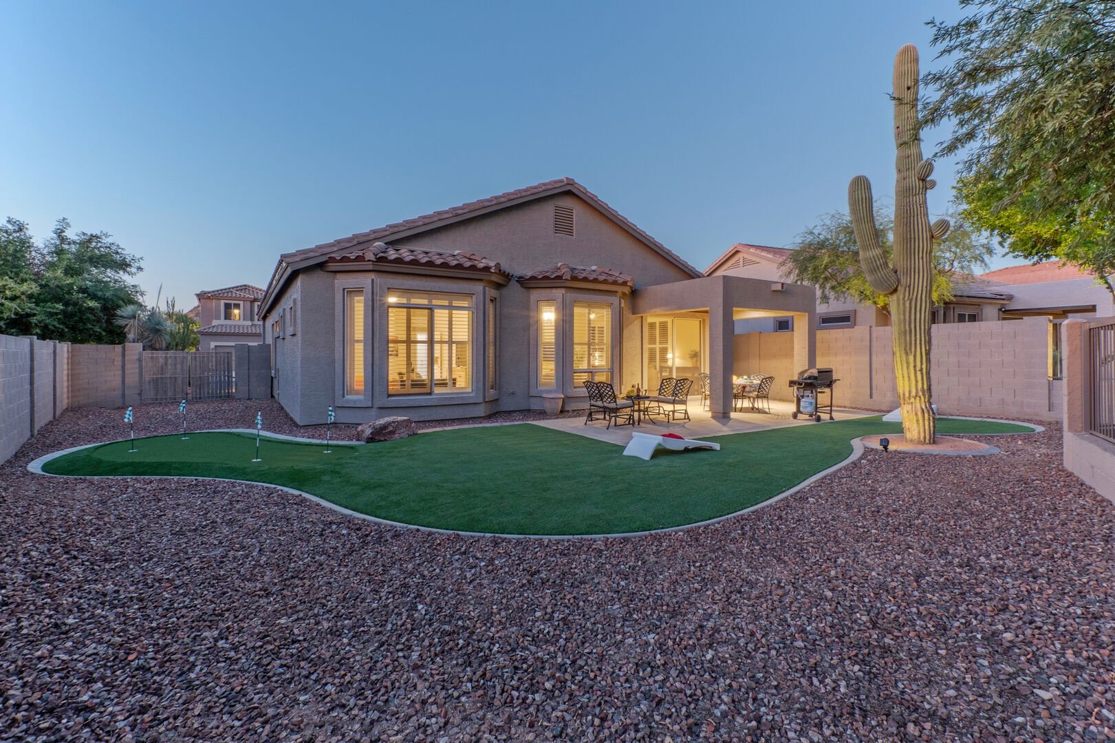 Desert home exterior at dusk with private putting green and saguaro cactus