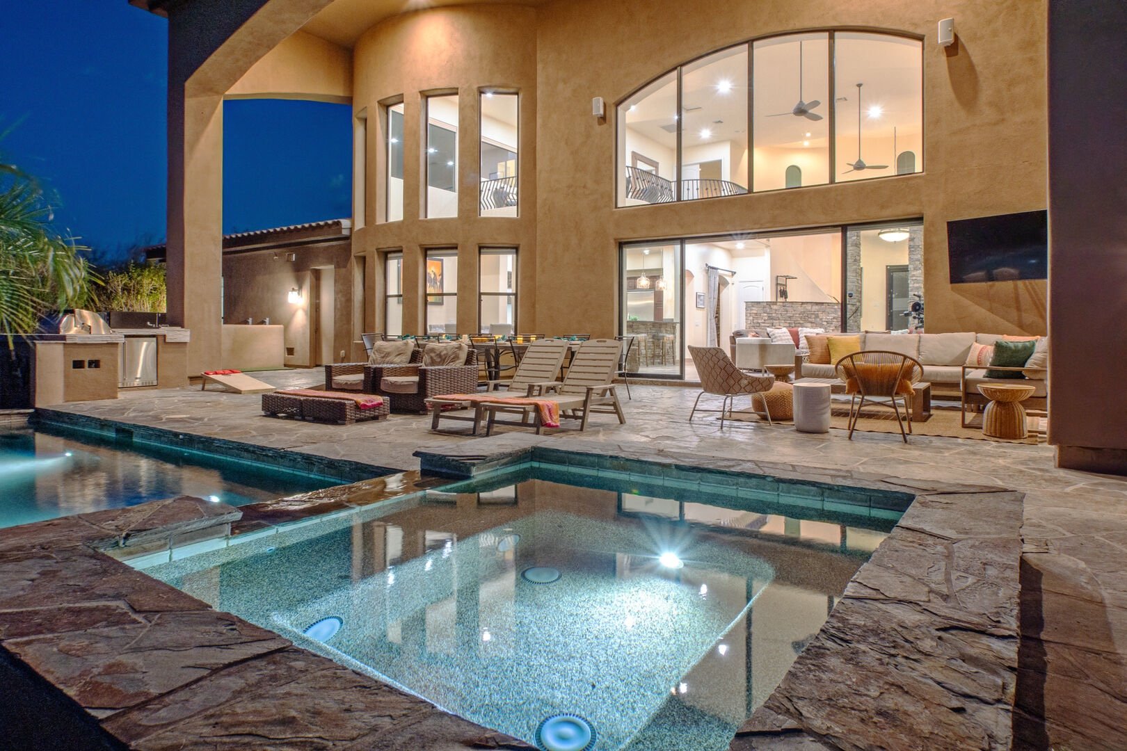 Pool and spa at night with patio seating