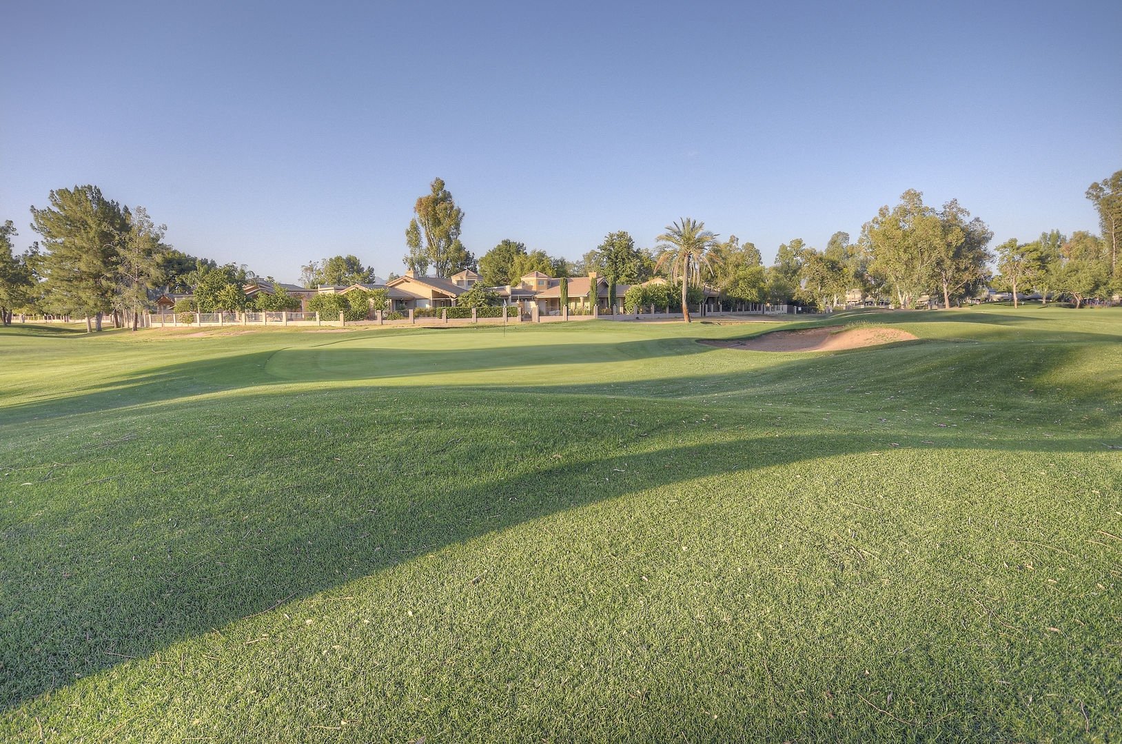 Golf course fairway with sand bunker and tree-lined homes