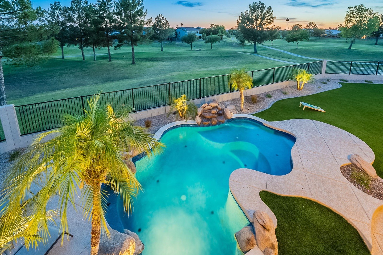 Backyard pool and putting green overlooking golf course at dusk