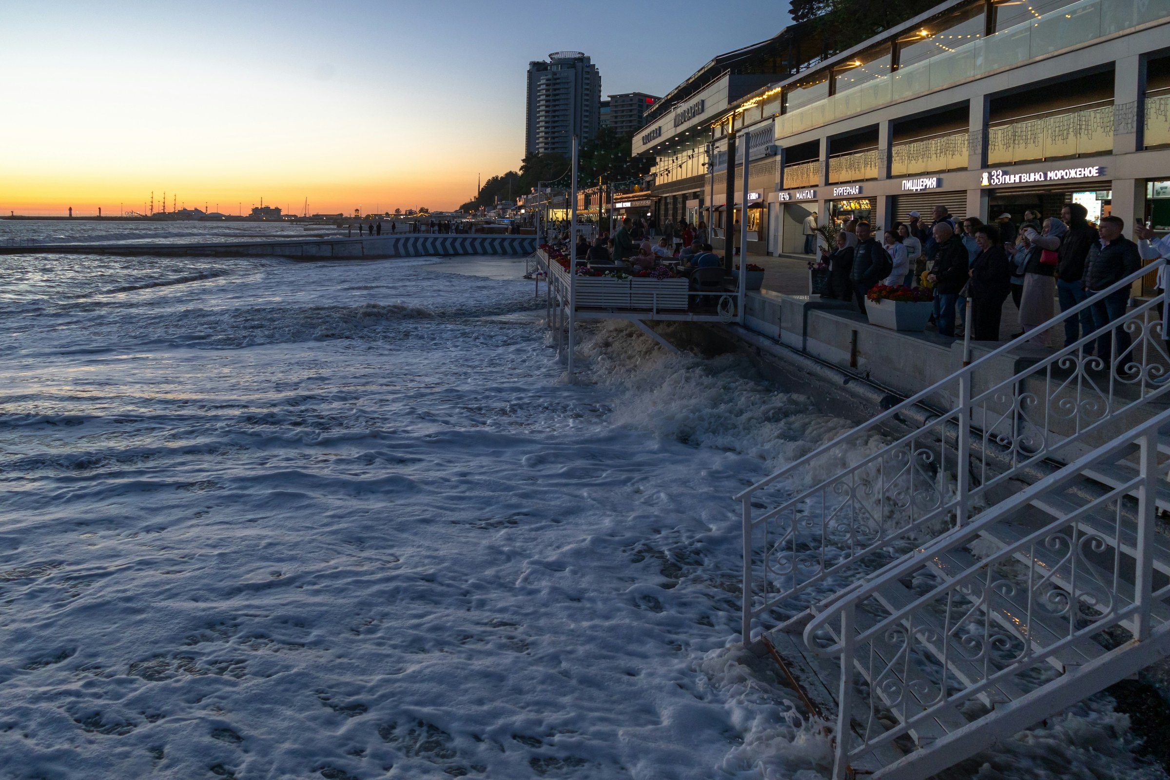 Cocoa Beach Pier at dusk with surfers in the water and restaurant lights along the deck