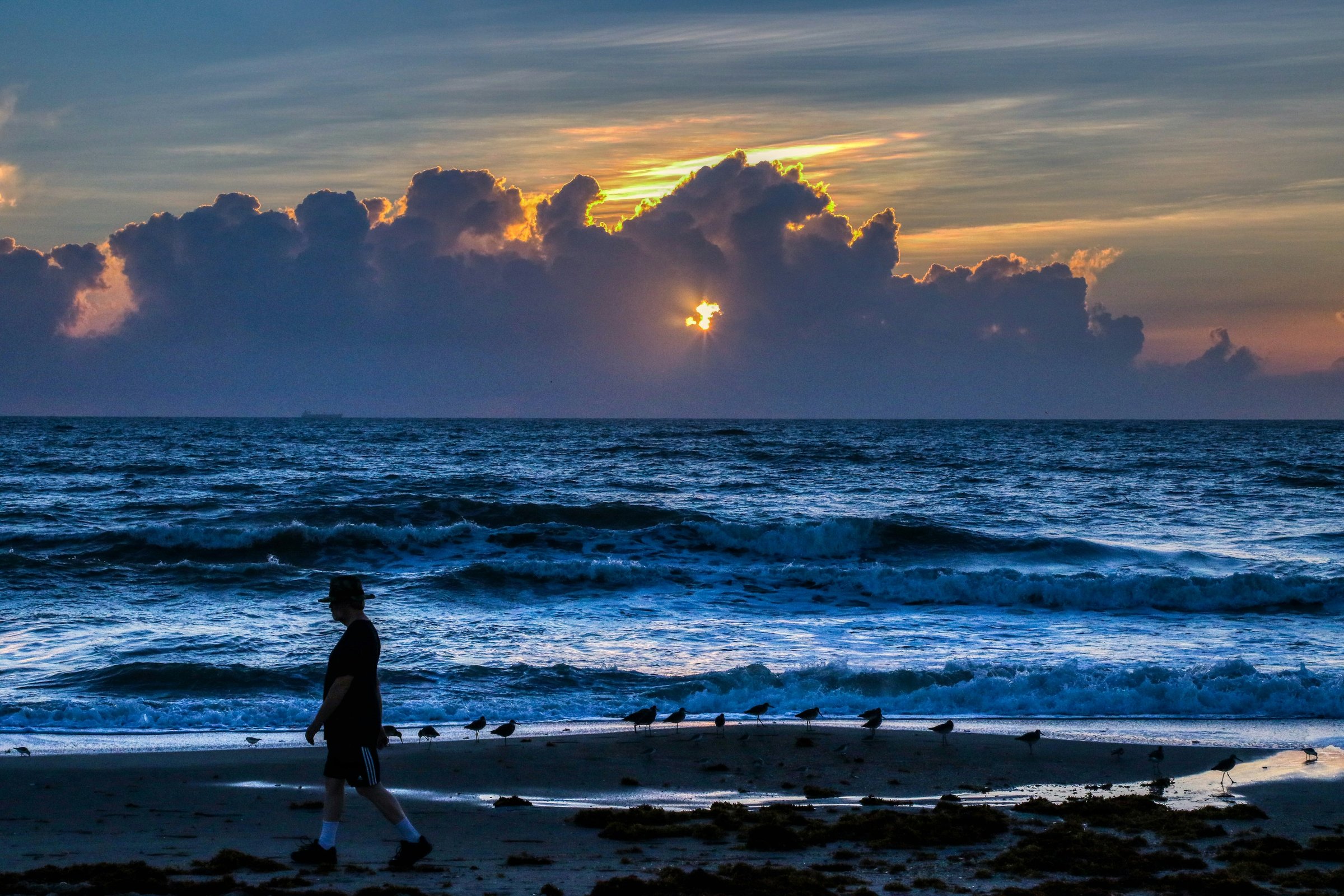 Evening view of the Atlantic from Cocoa Beach, Florida, with a rocket contrail rising to the north over the water
