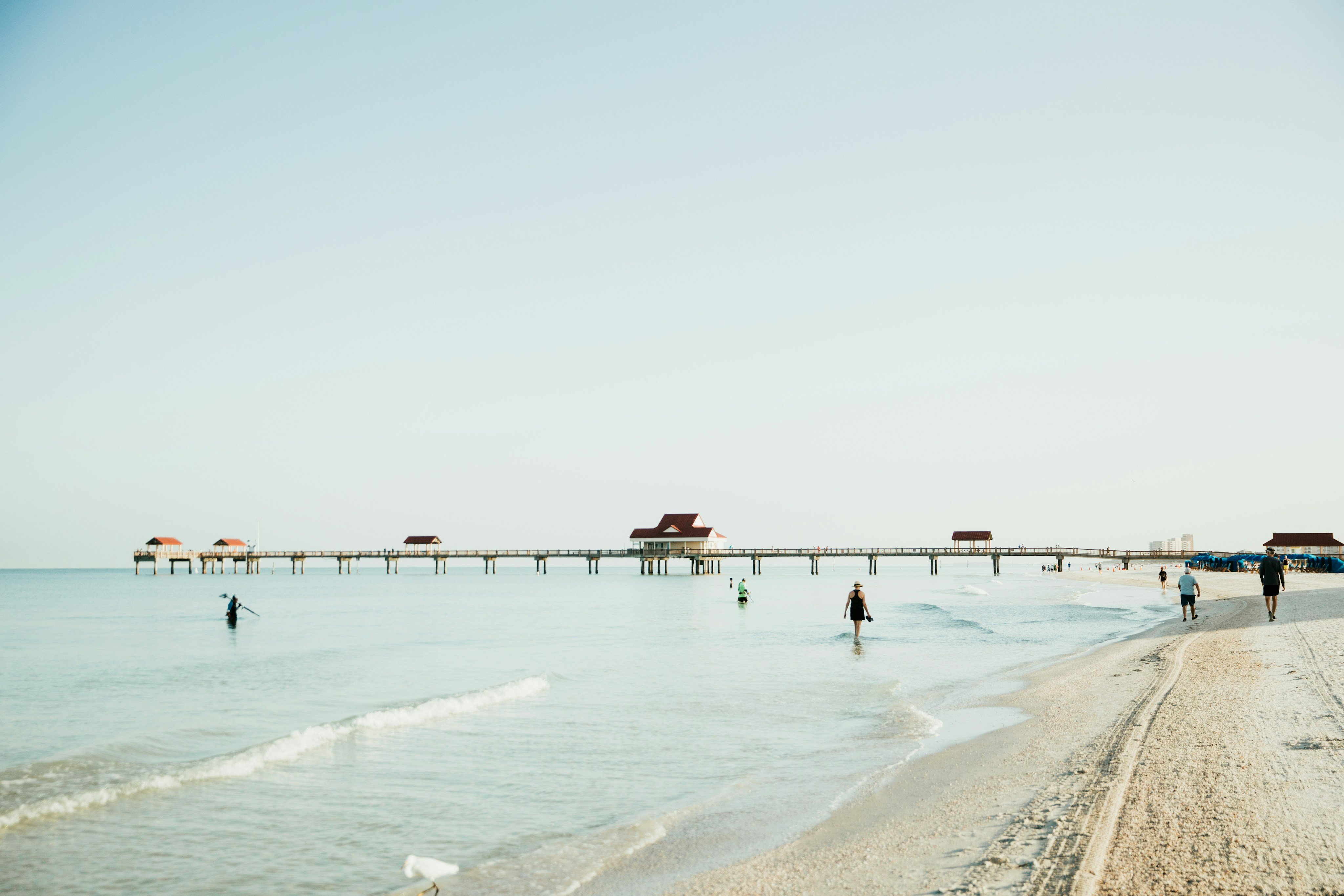 Clearwater Beach pier with calm shallow water and people wading, Florida