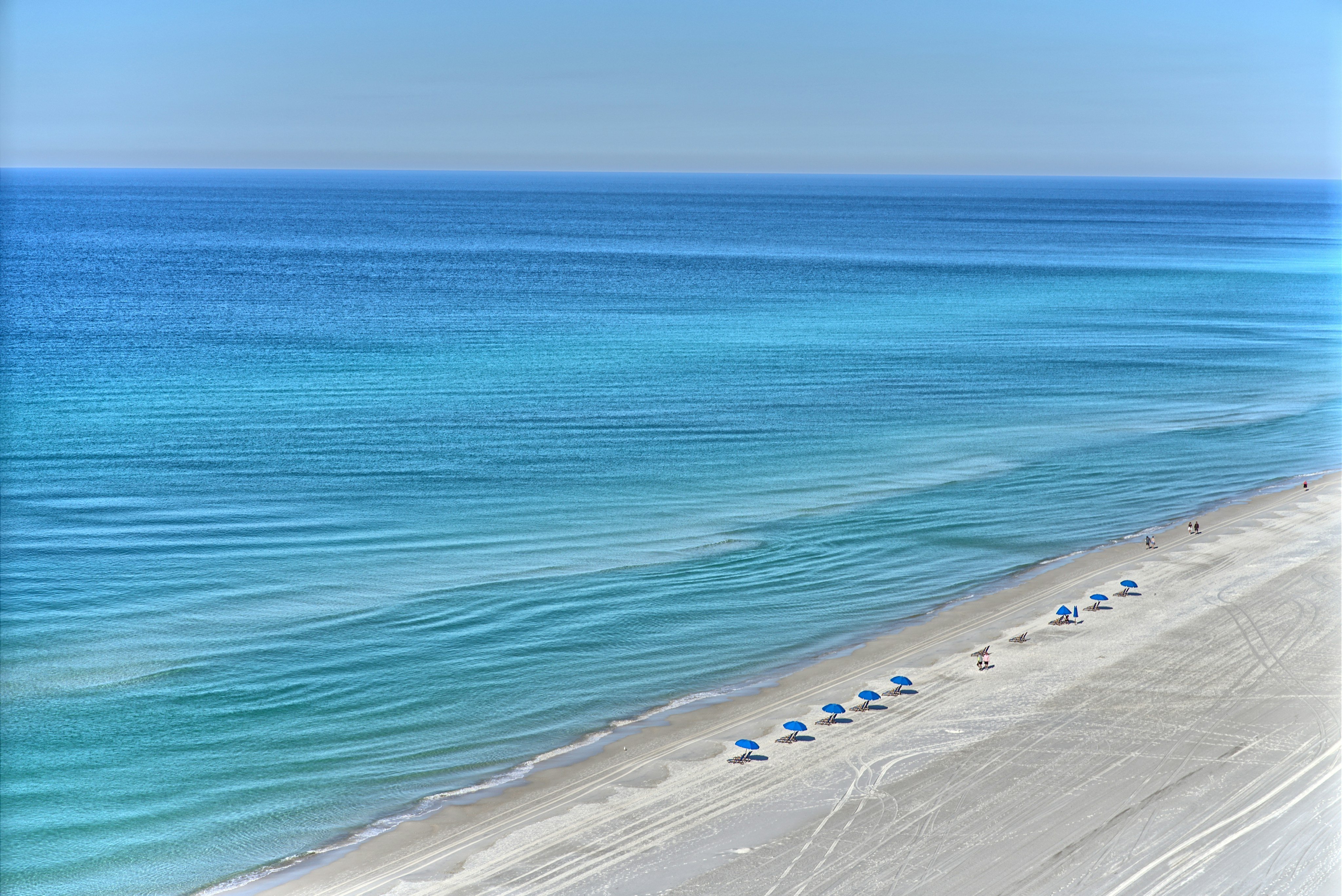 Aerial view of white sand beach with turquoise water and blue umbrellas, Anna Maria Island, Florida
