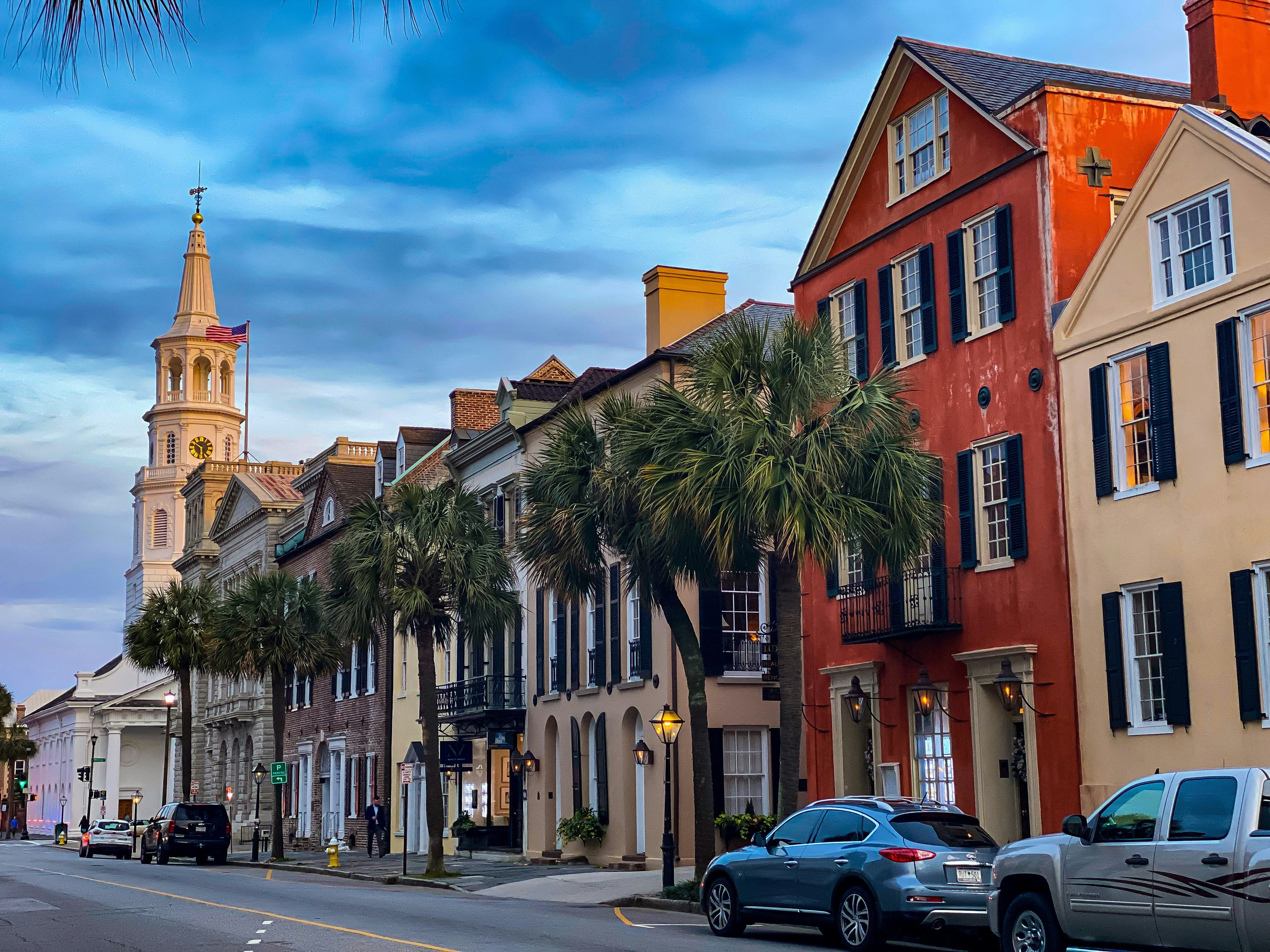 Historic downtown Charleston at dusk, with St. Michael's steeple rising above the palm-lined street