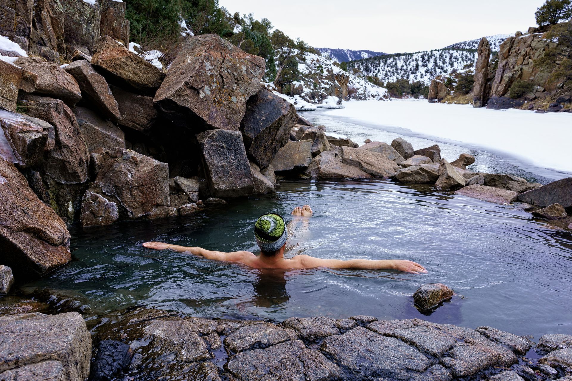 Man relaxing in a natural hot spring near Teton Valley, Idaho with mountain views