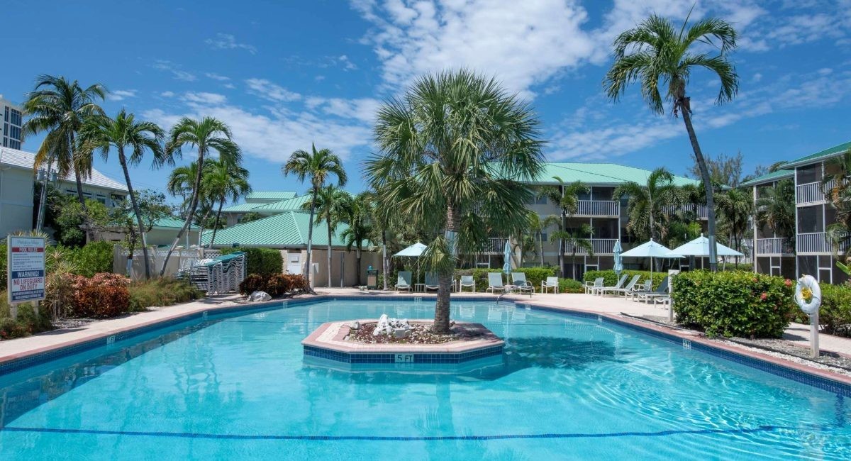 Plantation Village Beach Resort pool area on Seven Mile Beach featuring tropical landscaping, palm trees, and vacation rental condos with beachfront access