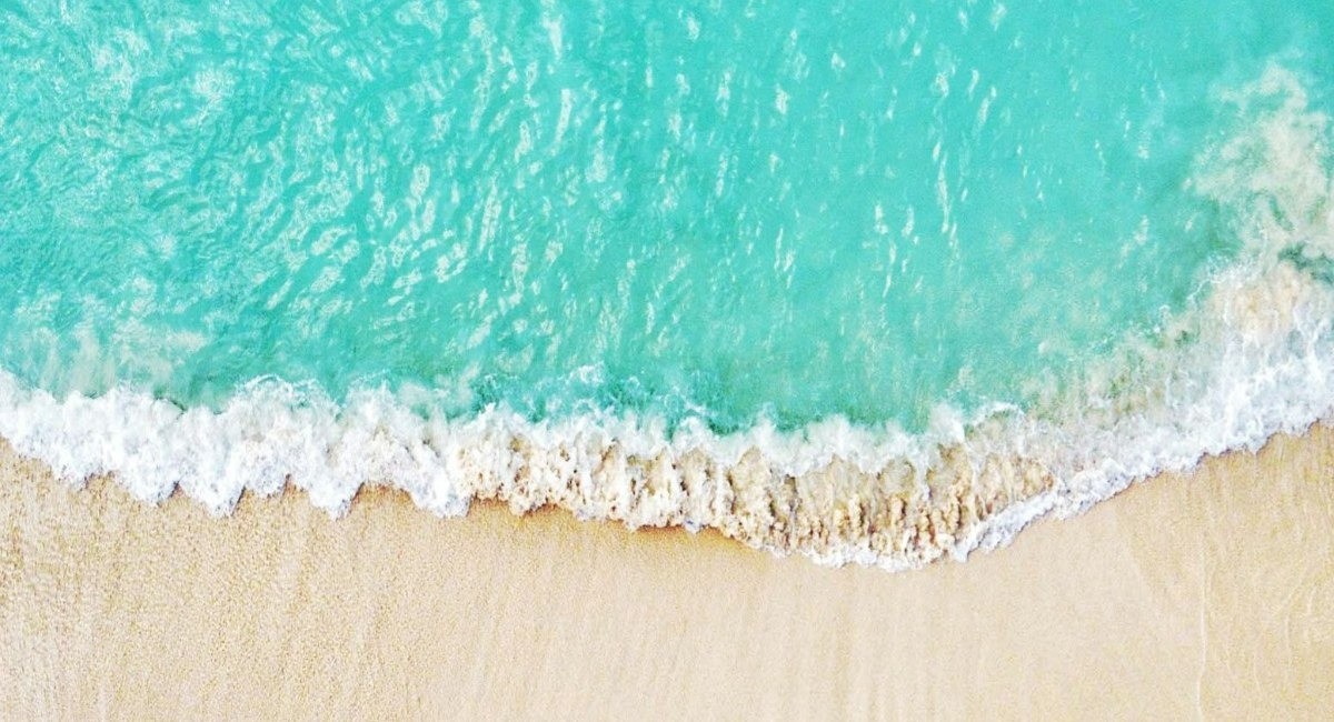 Turquoise water lapping onto a white sand beach in Grand Cayman