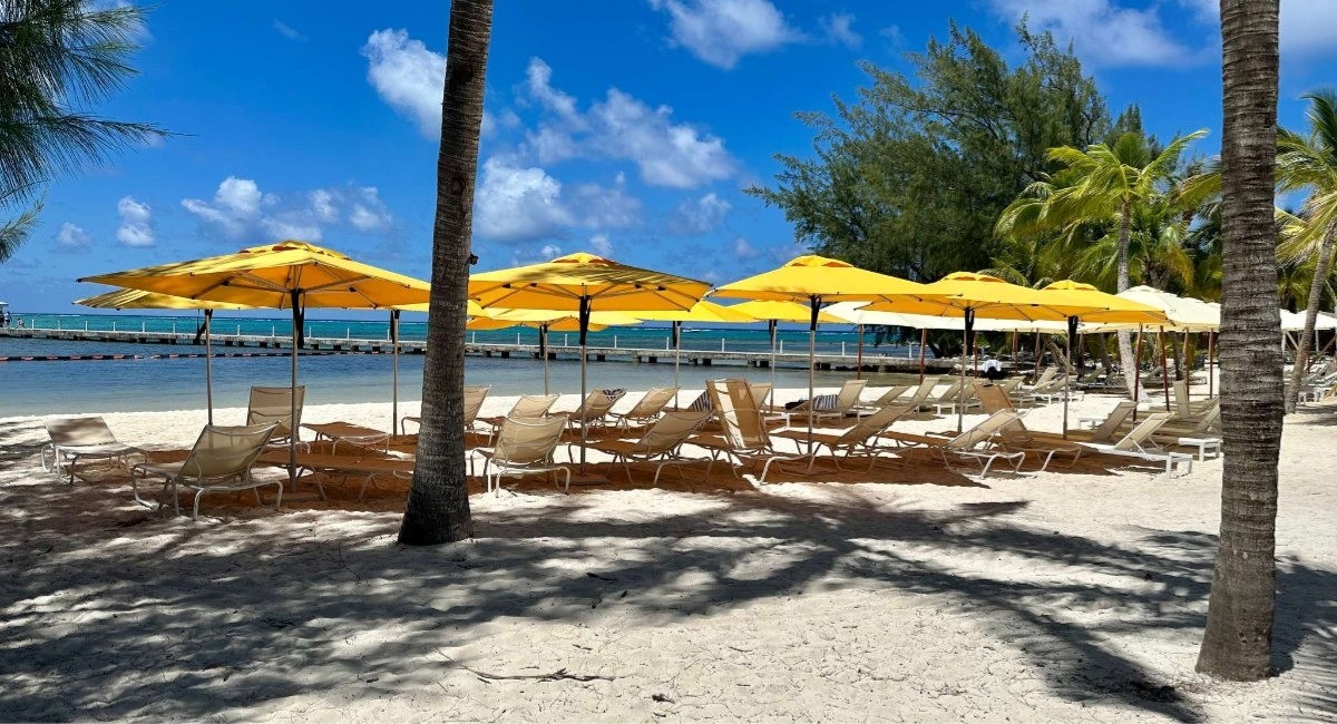 Sun loungers and yellow umbrellas on a quiet white sand beach in Grand Cayman