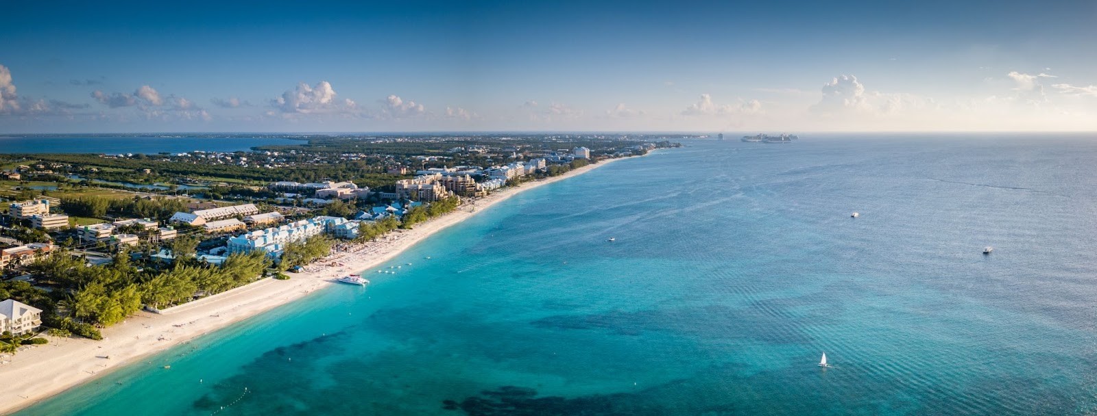 Aerial view of Seven Mile Beach Grand Cayman showing pristine white sand, crystal-clear turquoise waters, and beachfront resorts along the Caribbean coastline