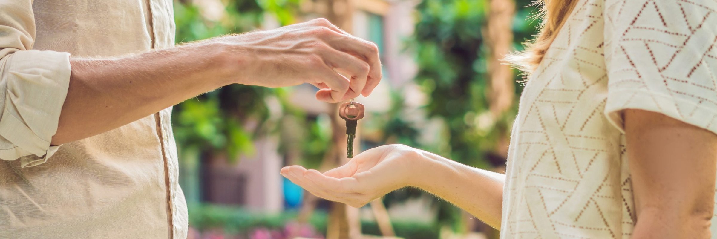 Handing keys over for short term rental two people with extended arms one dangling keys
