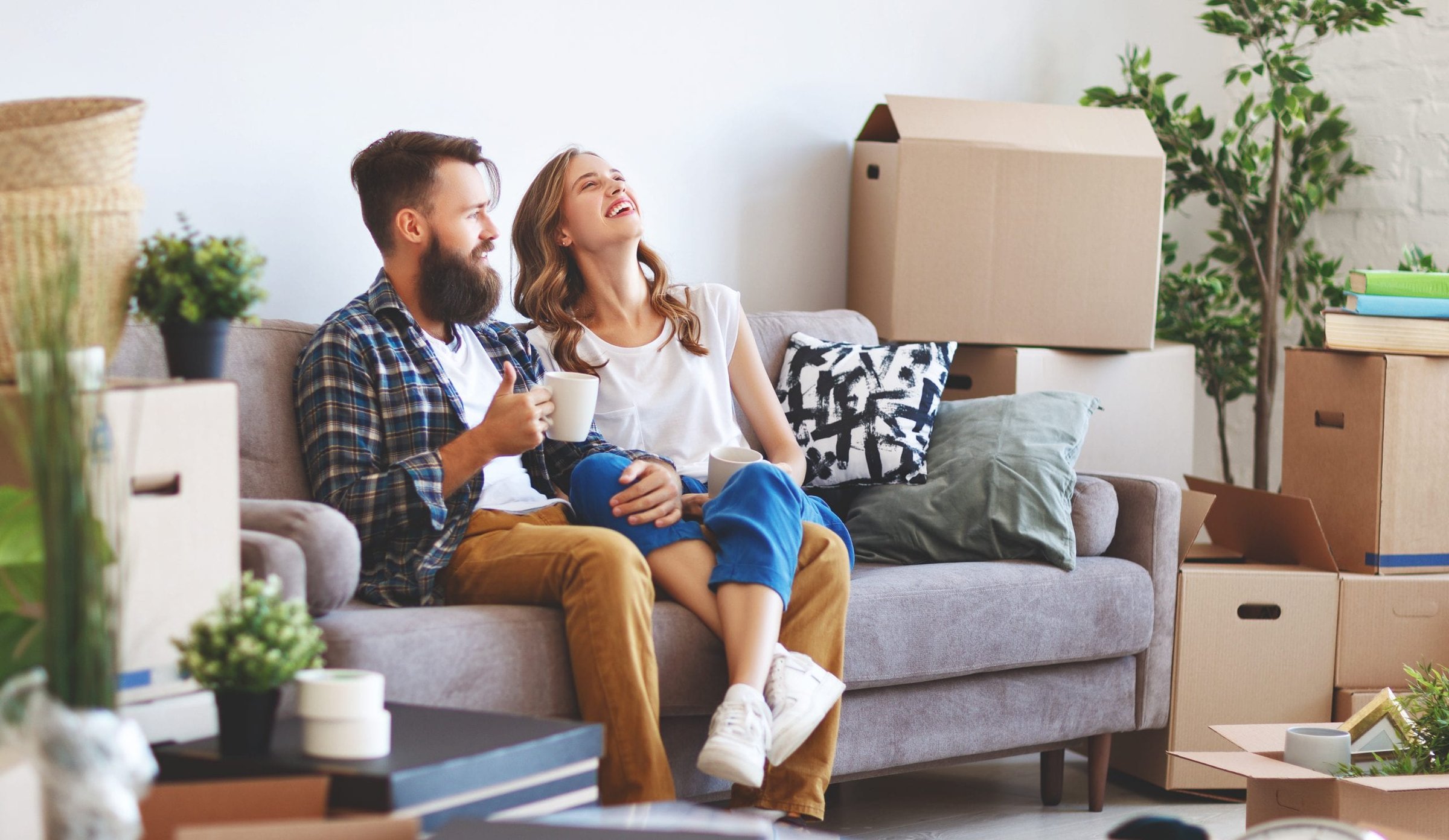 Young couple sitting on couch with moving boxes around