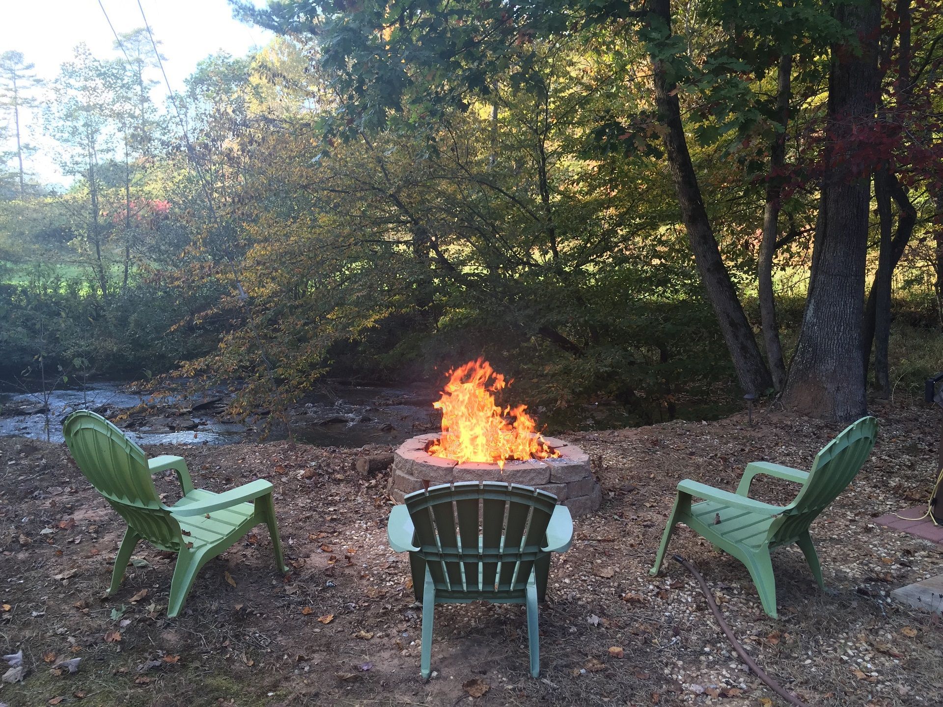 Three green chairs around a fire pit at dusk at one of our vacation cabin rentals in north Georgia, Blue Ridge