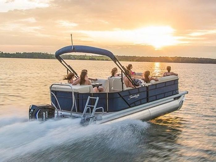 People enjoying a sunset pontoon boat ride on calm water.