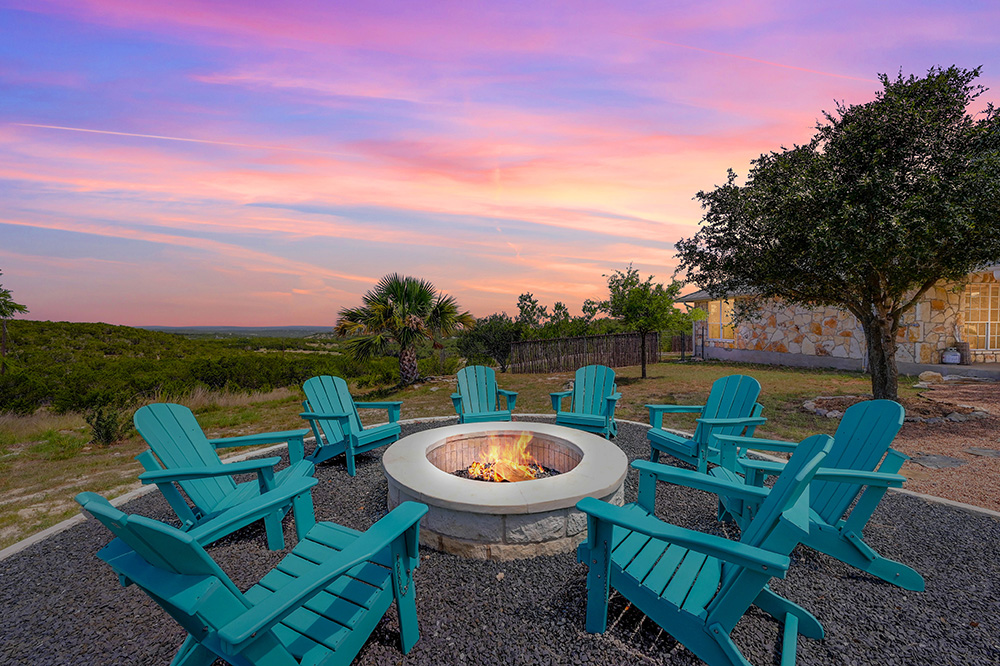 A roaring fire pit overlooking the scenic Texas Hill Country at sunset in Dripping Springs, Texas.