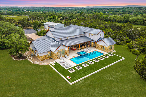 An aerial view of a large vacation rental property showing a high-end home, pool, and patio.