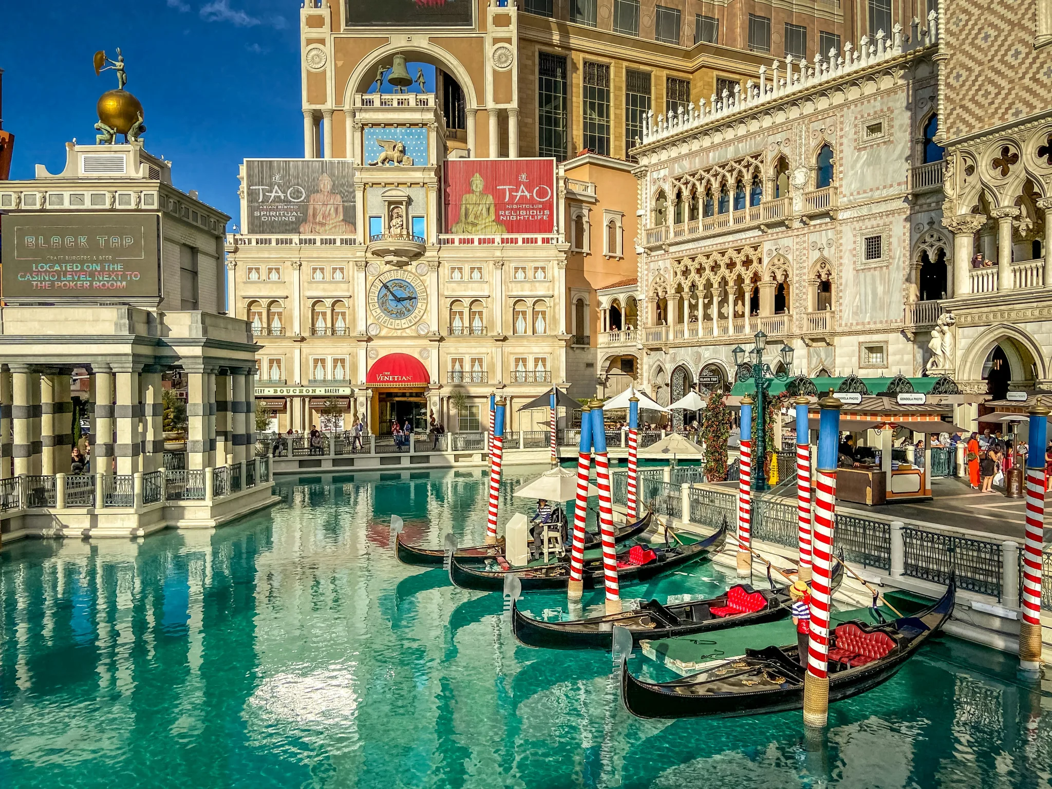 It appears to be Venice, with aqua canals, gondola boats with red and white striped posts, and Venetian style stone-faced buildings, but this is the indoor attraction in Las Vegas, called The Venetian.