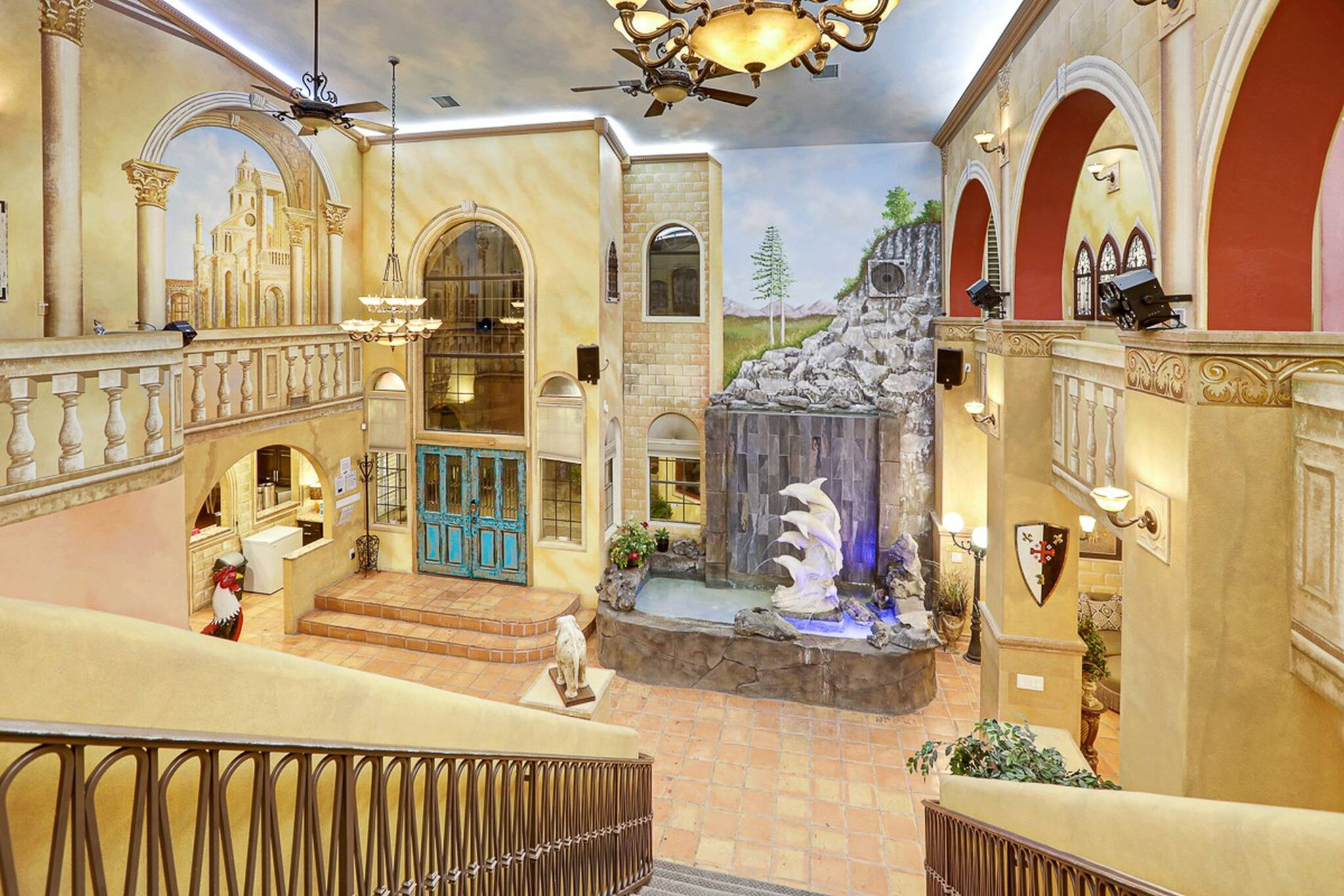 The grand and elegant entrance to D&D Mansion, a rental home in Vegas, showcases a grand staircase and roman-style stone interior.