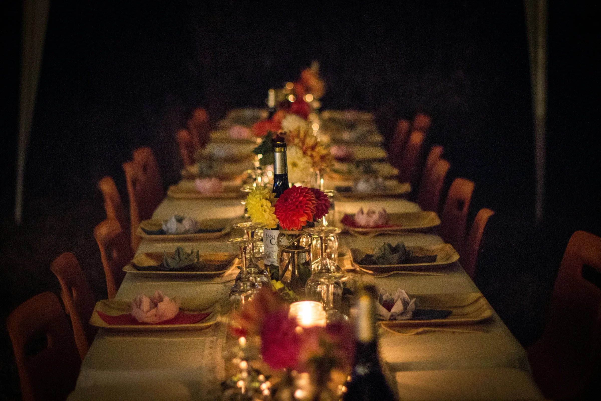 An elegant candlelit table is set with plates, napkins and flowers
