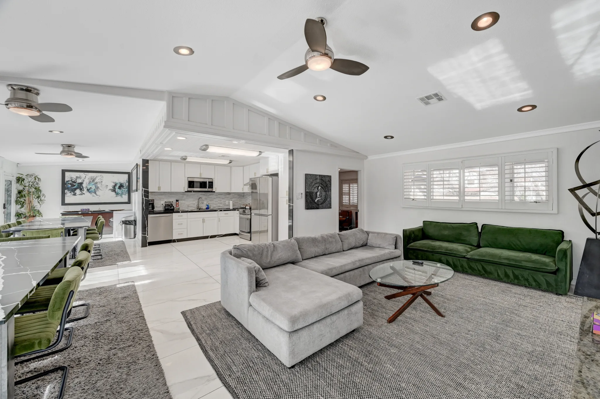 A large luxurious living space in a Vegas luxury rental features large sectional couches in a living room, a large dining area for groups, and a kitchen with bright natural light.