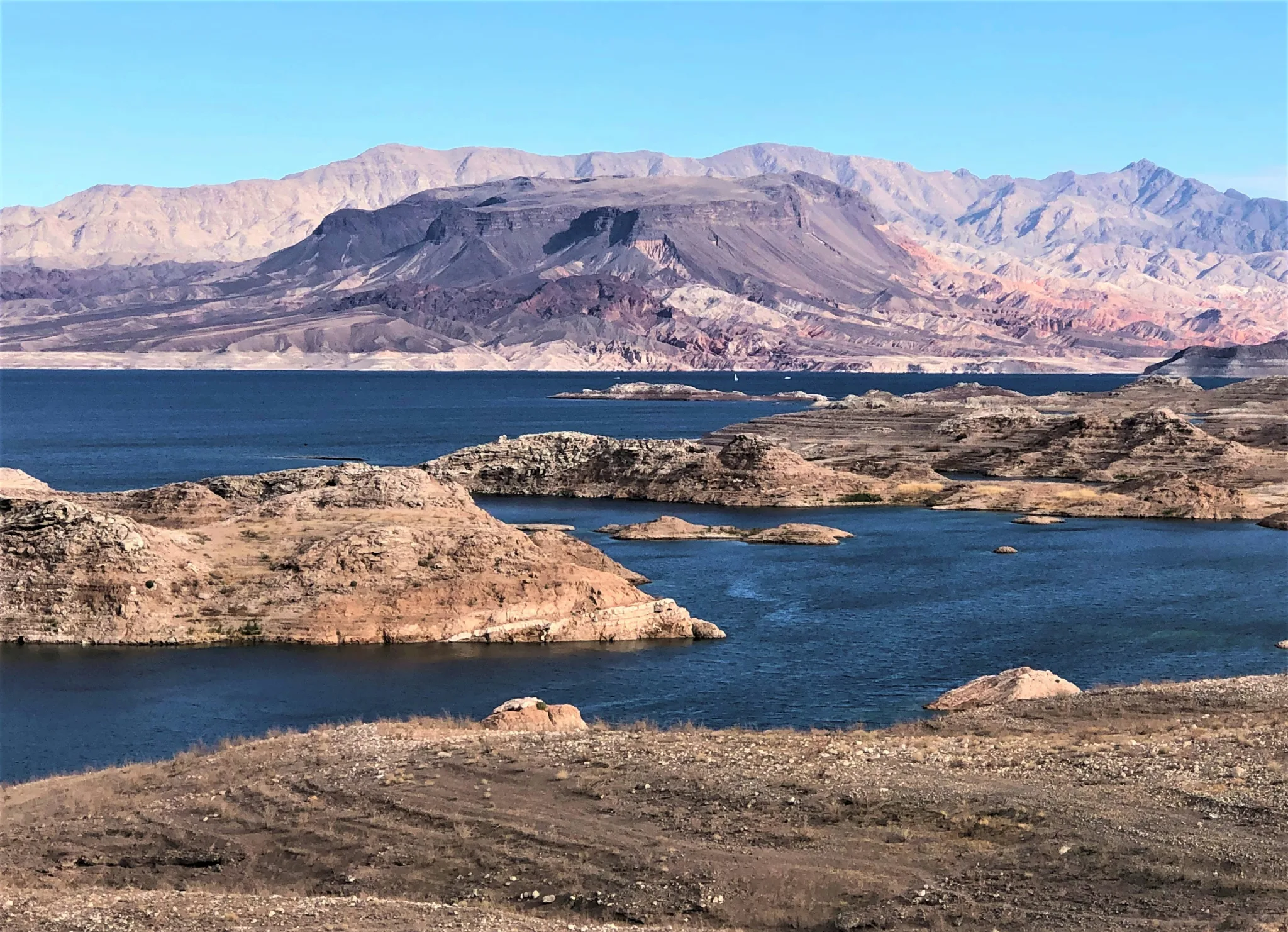 A view from Sunset Point at Lake Mead National Recreation Area, where desert landscapes of brown rock and sand meet dark blue waters.