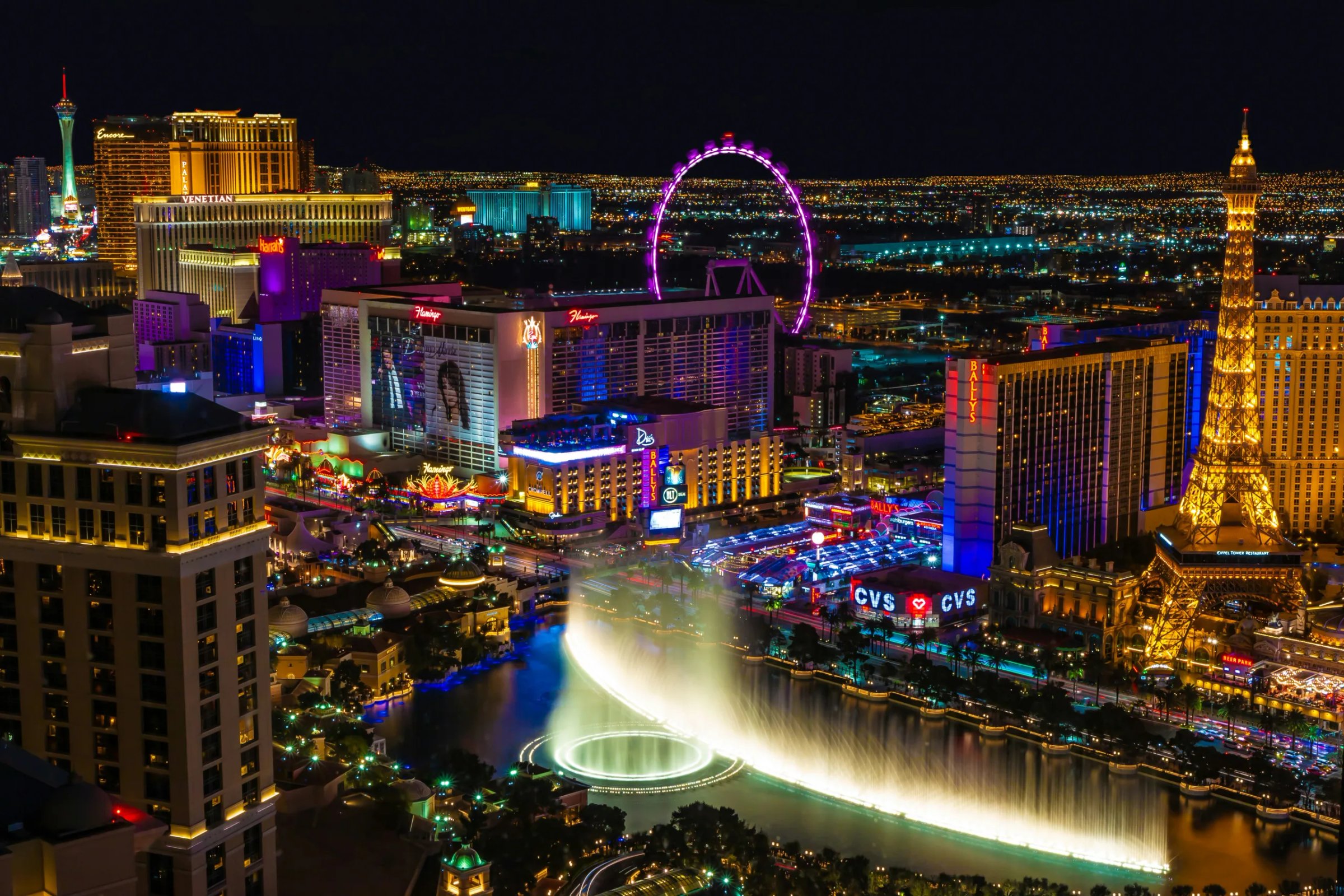 Las Vegas pictured at night, with lights shining from the Venetian, Flamingo and other hotels, and the Bellagio fountain show in the foreground