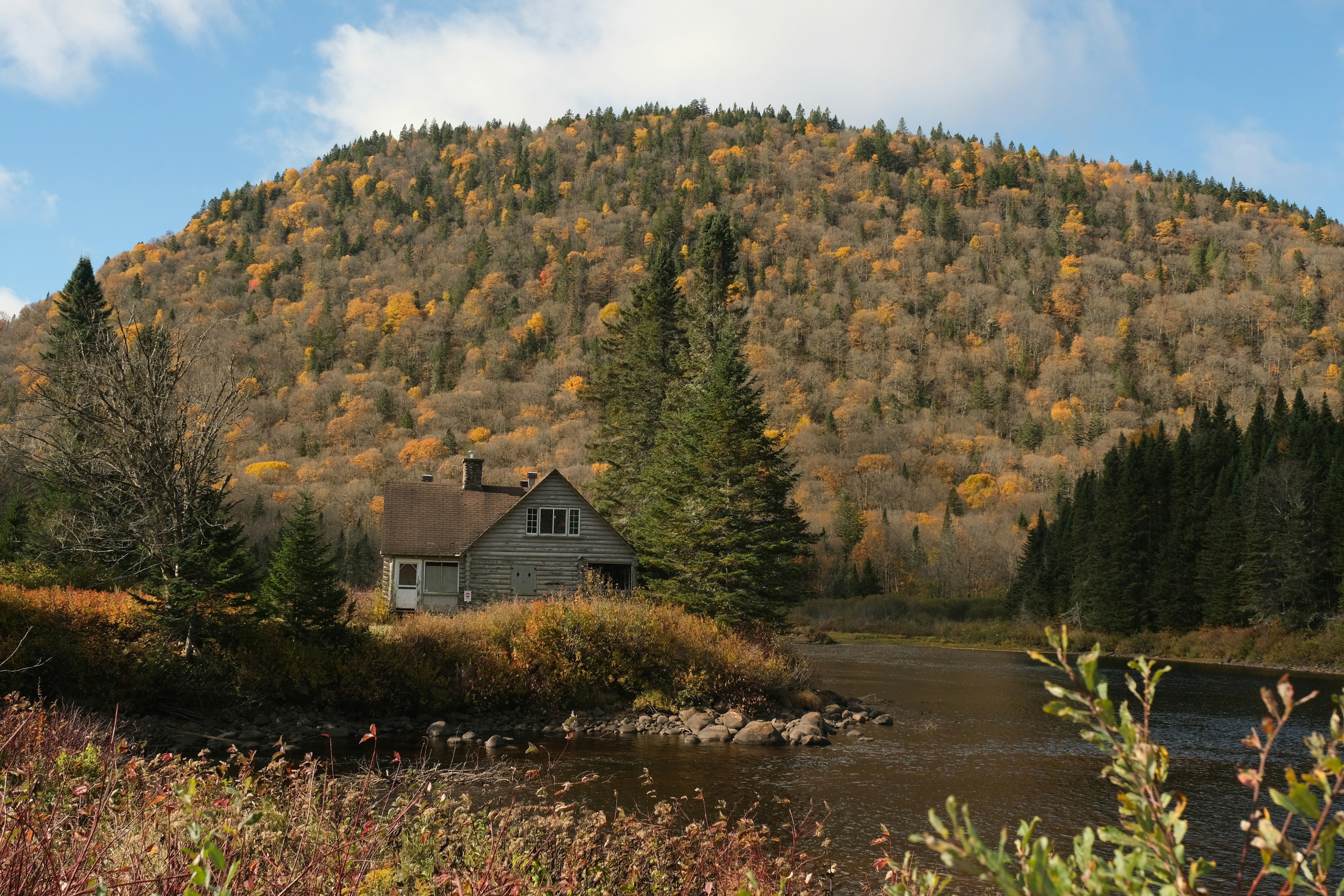 Cabin by a river with autumn mountain foliage