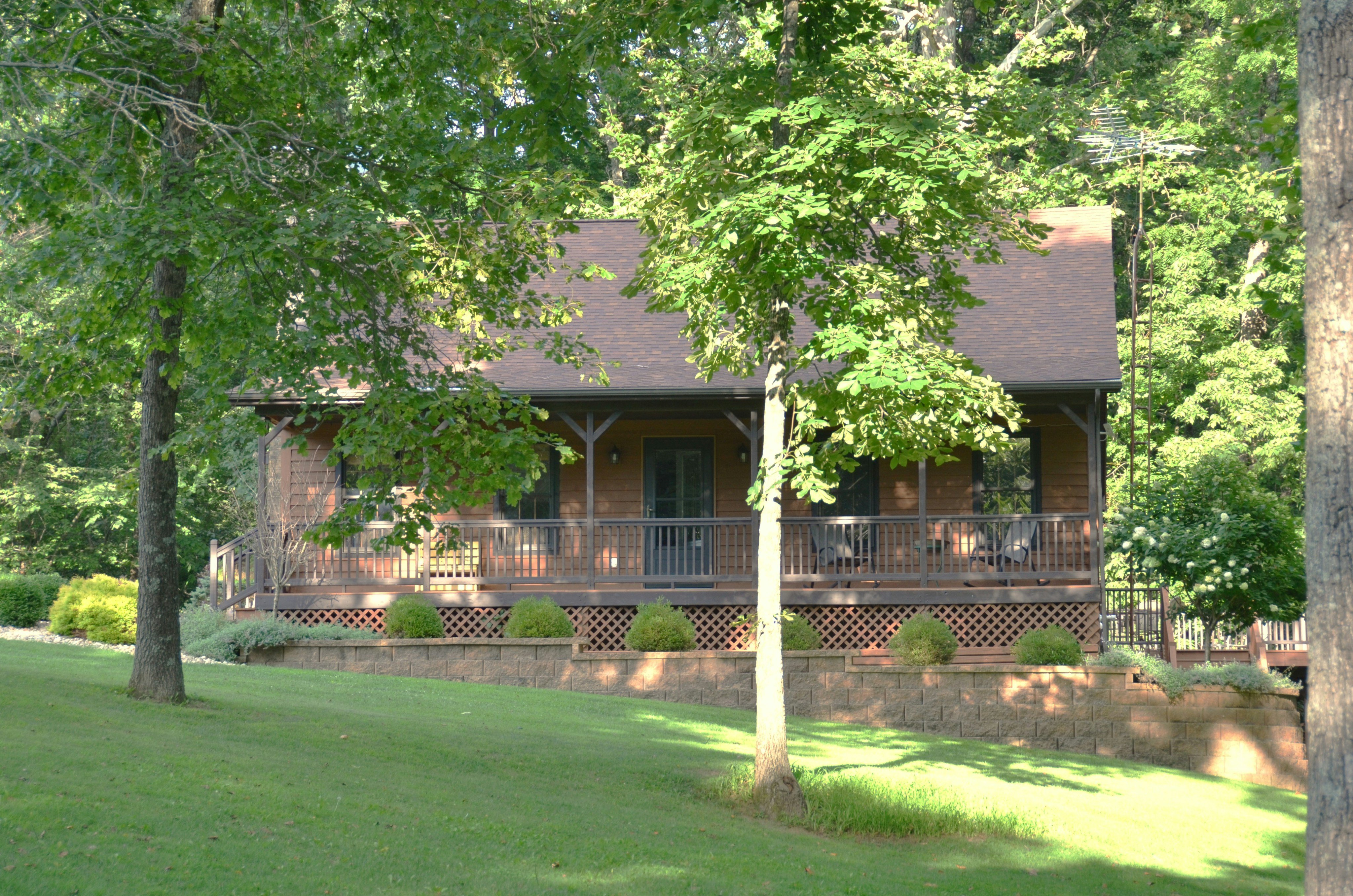 Country cabin with front porch surrounded by green trees