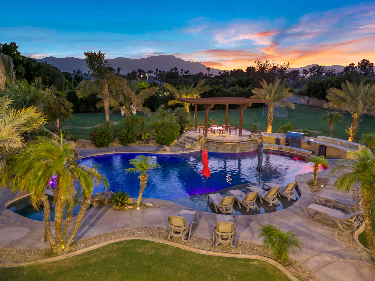 Aerial view of Yucca Dunes at sunset, the courtyard and pool framed by California desert mountains