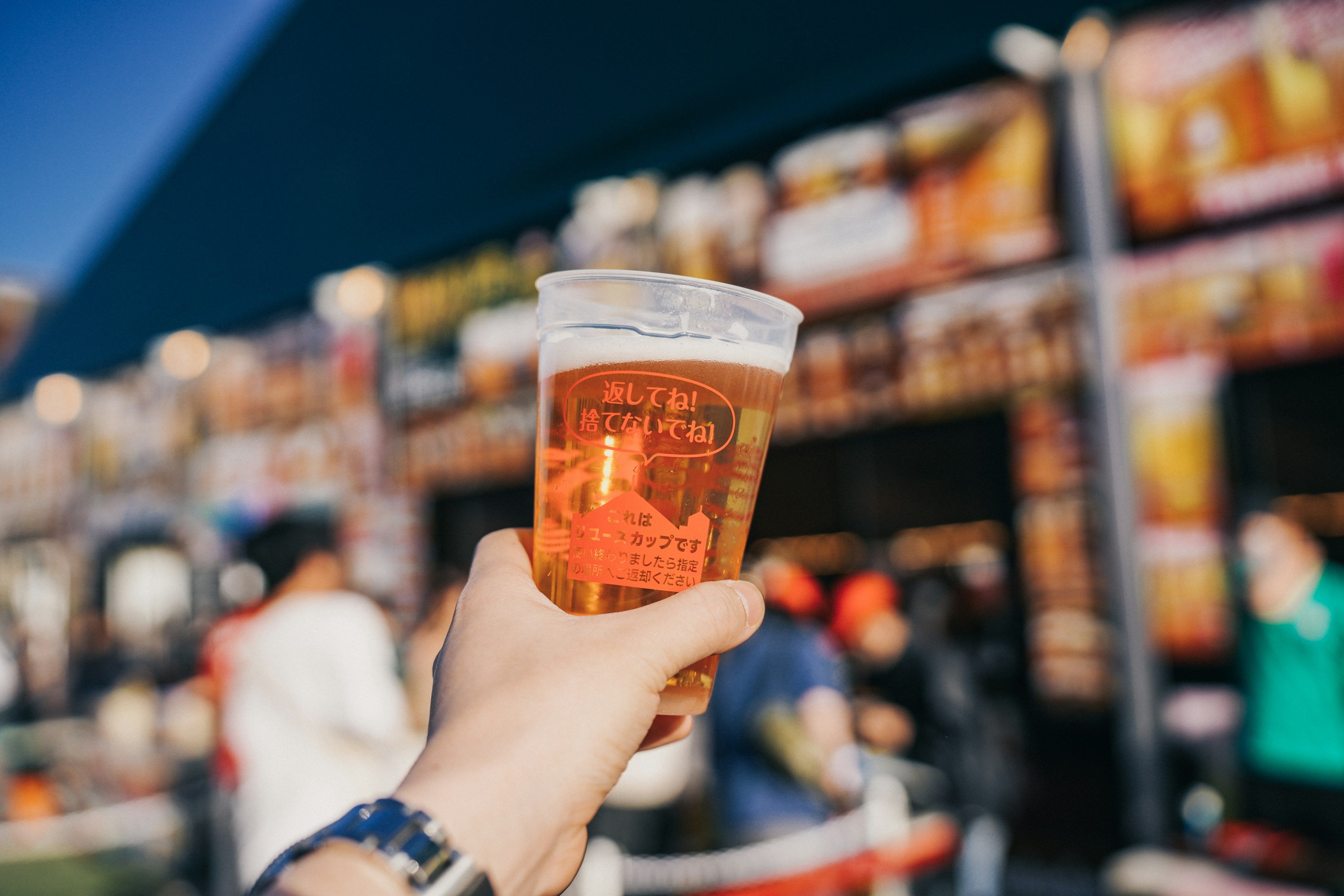 Cold beer raised at a sunny outdoor festival celebration