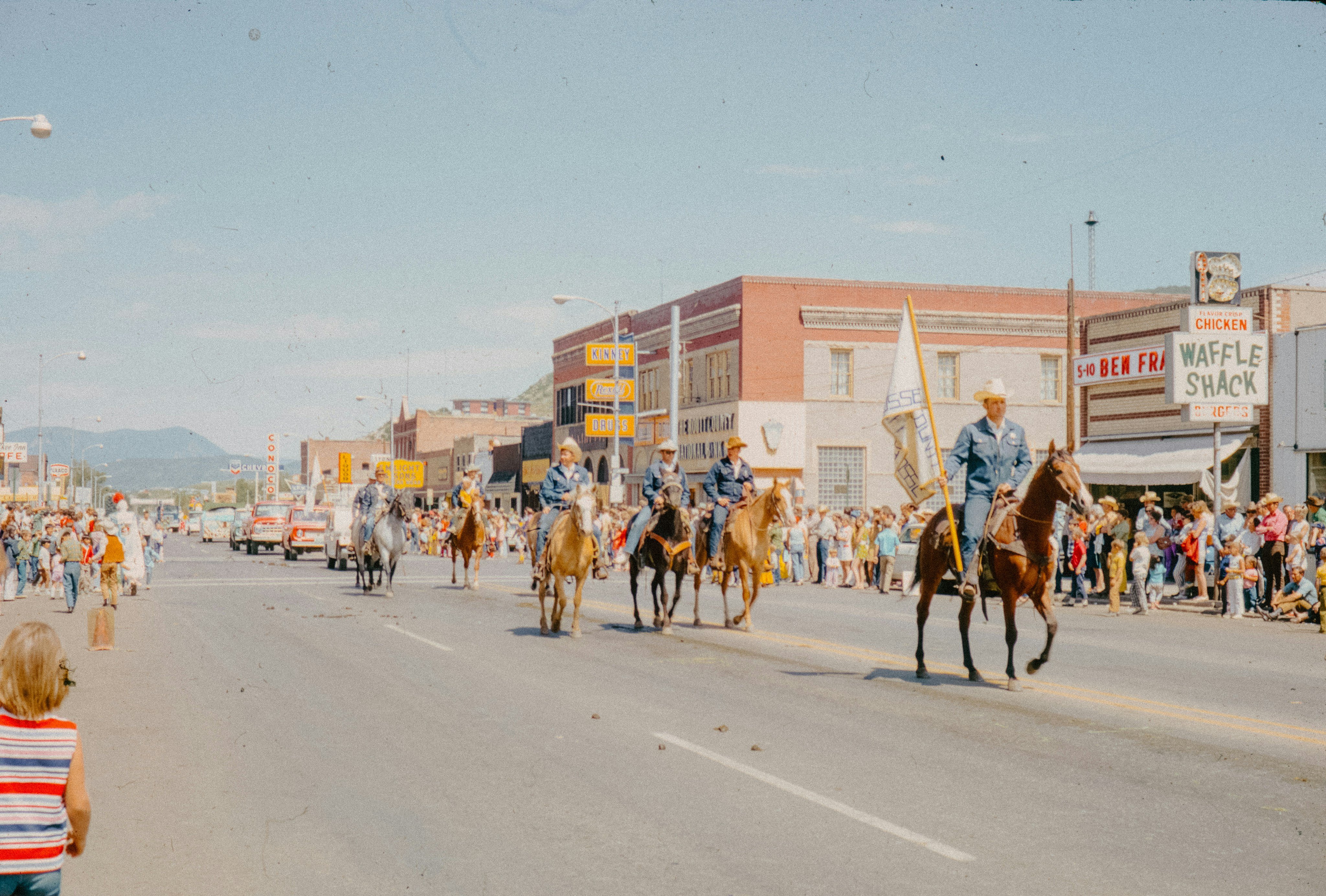 Cowboys on horseback riding through a small Western town parade
