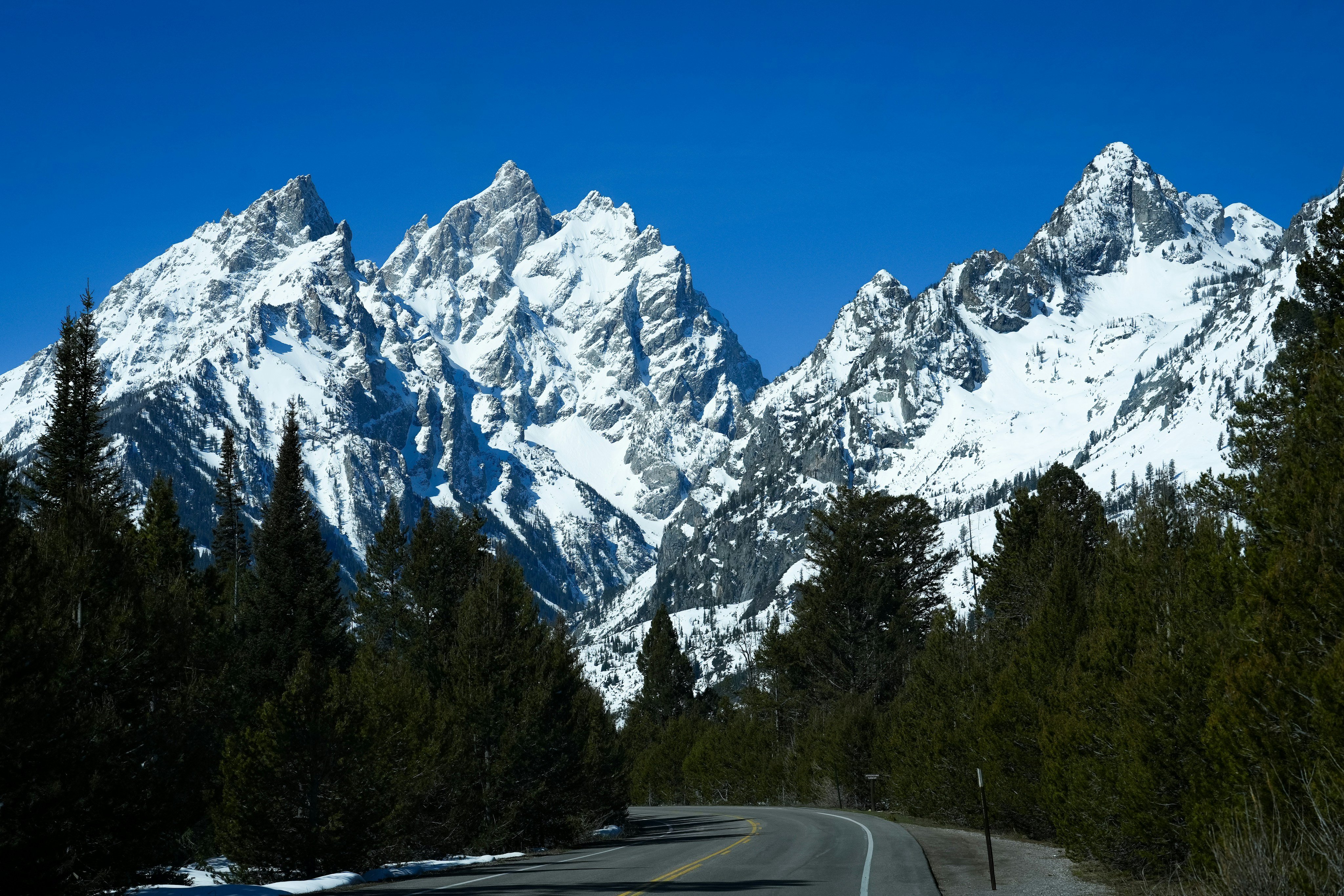 Mountain highway through Wyoming leading toward snow-capped peaks