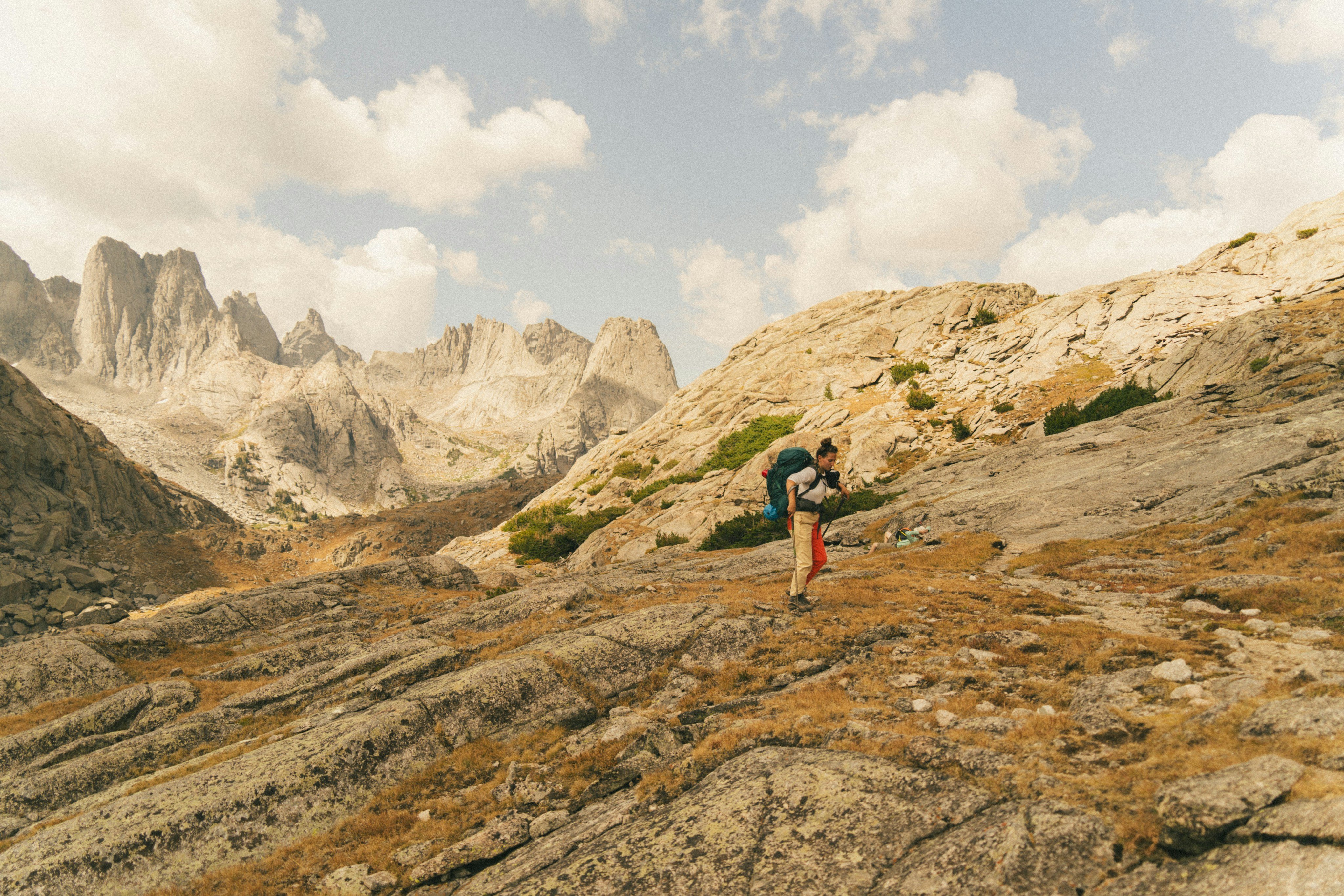 Runner scrambling rocky terrain with jagged mountain peaks, Wyoming