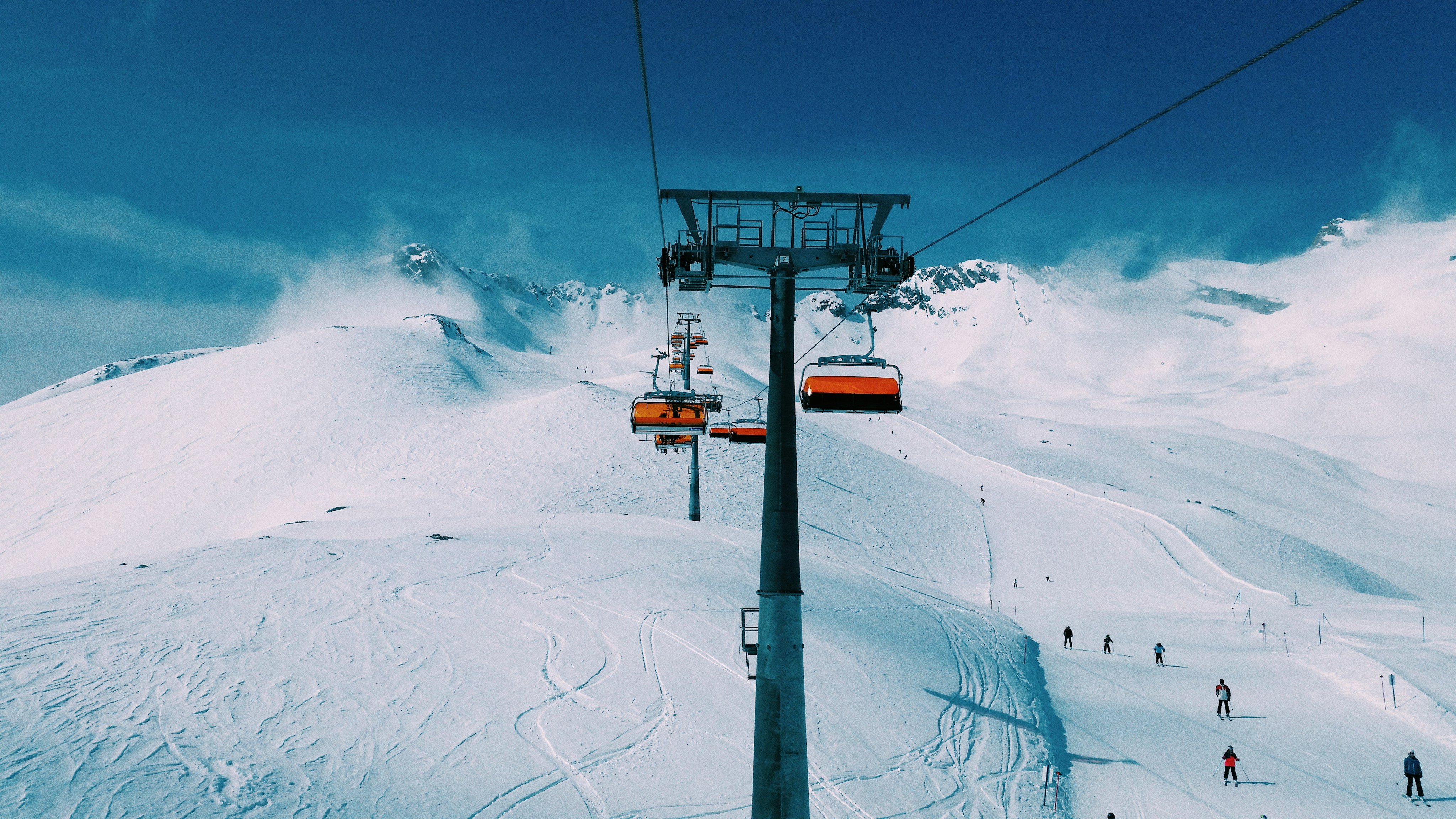 Chairlift rising over open ski terrain on a clear blue-sky day