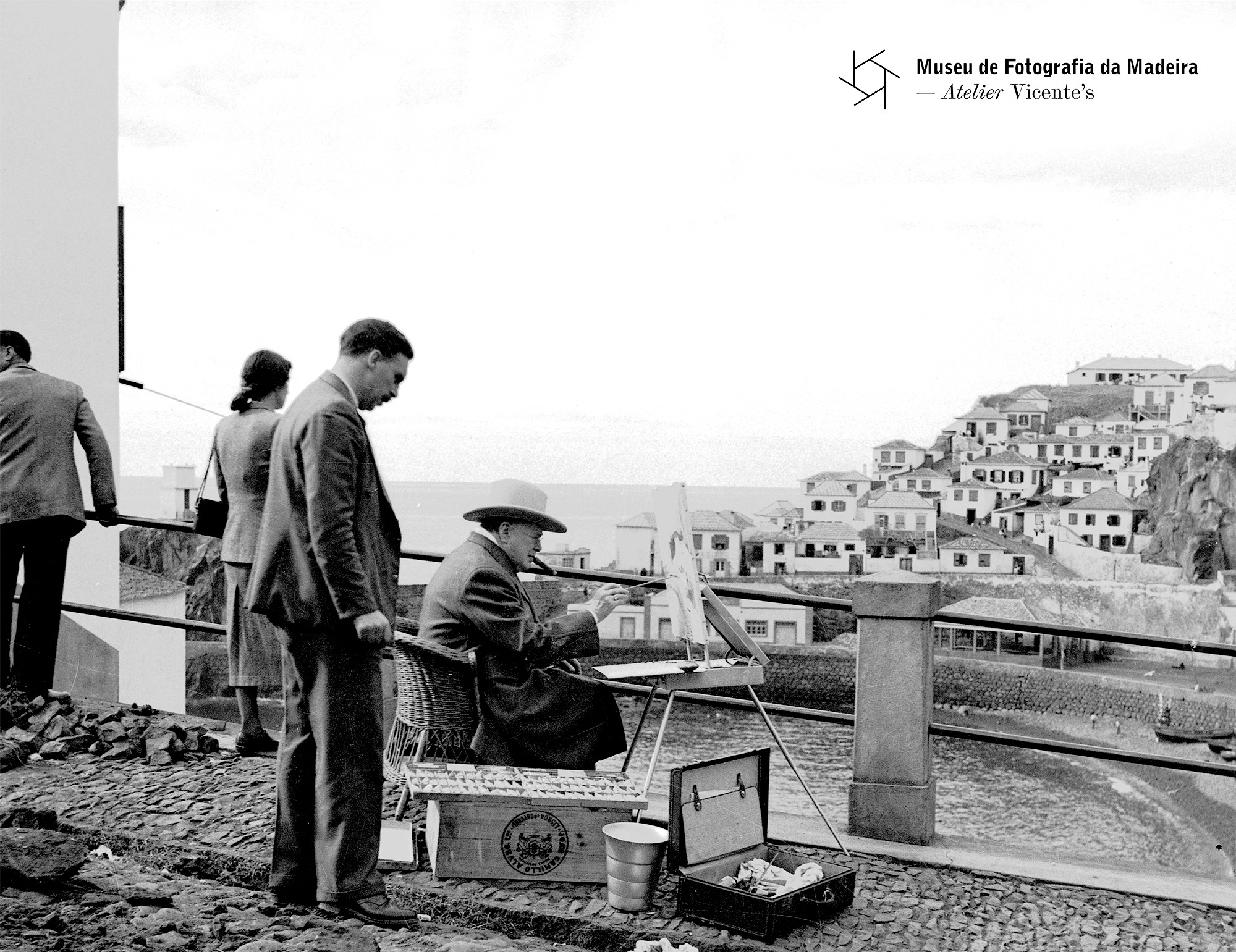 Winston Churchill painting in Câmara de Lobos, Madeira, in 1950, overlooking traditional houses by the bay.