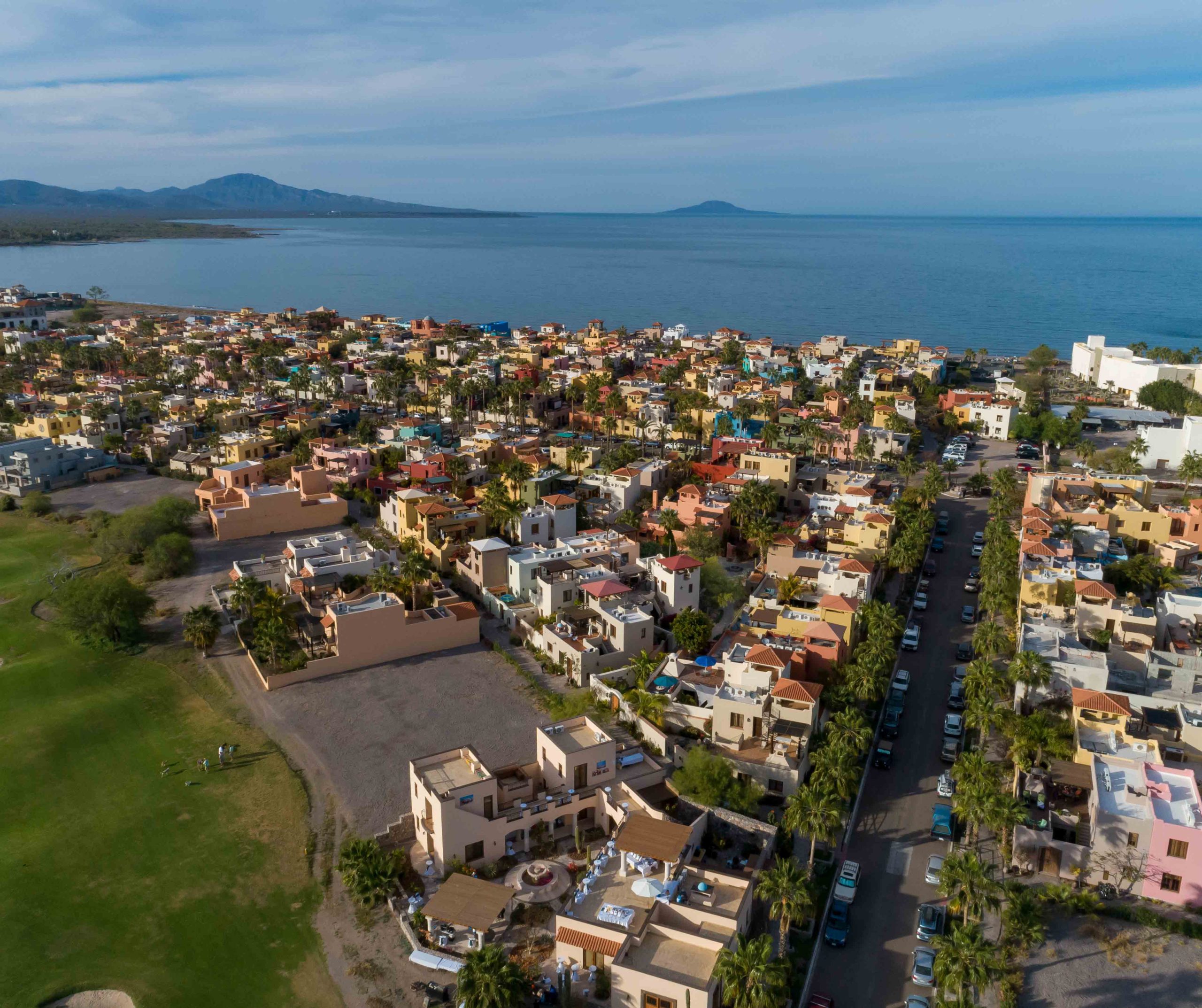 Aerial view of Loreto Bay town with colourful rooftops, palm trees, and the Sea of Cortez