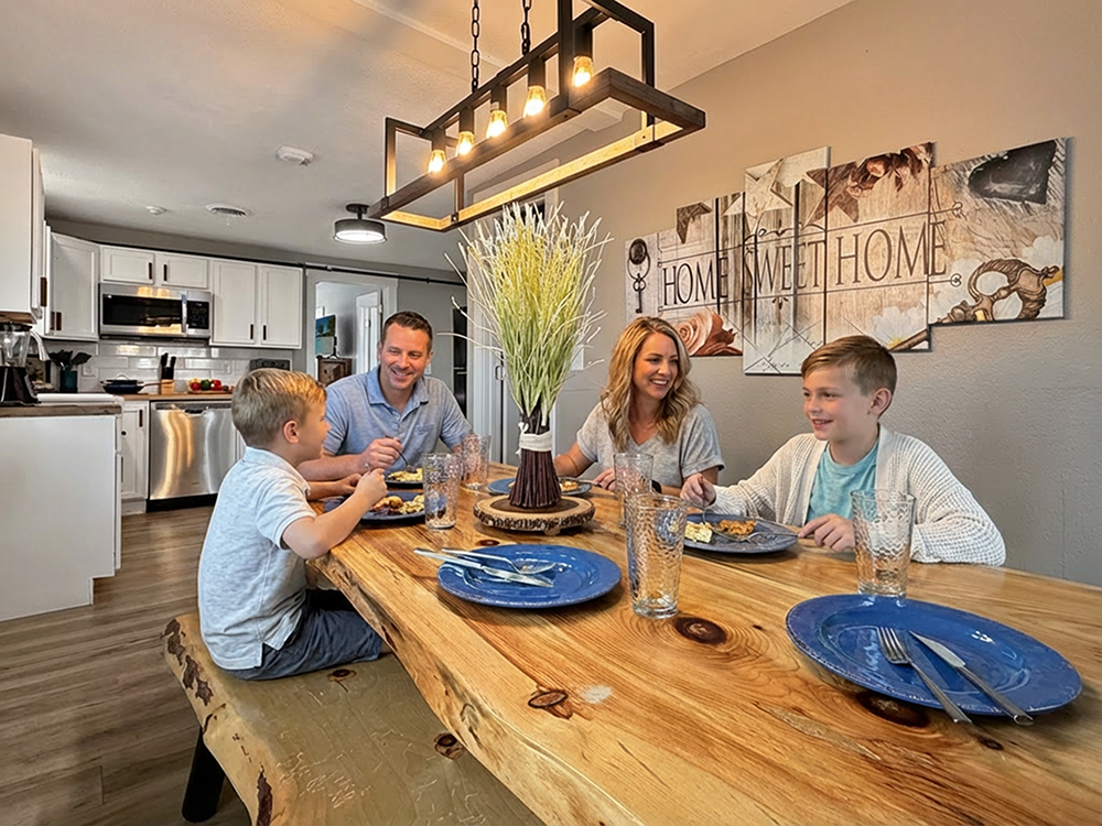 Happy family enjoying dinner together at a live-edge dining table in a Branson vacation rental with a fully equipped kitchen