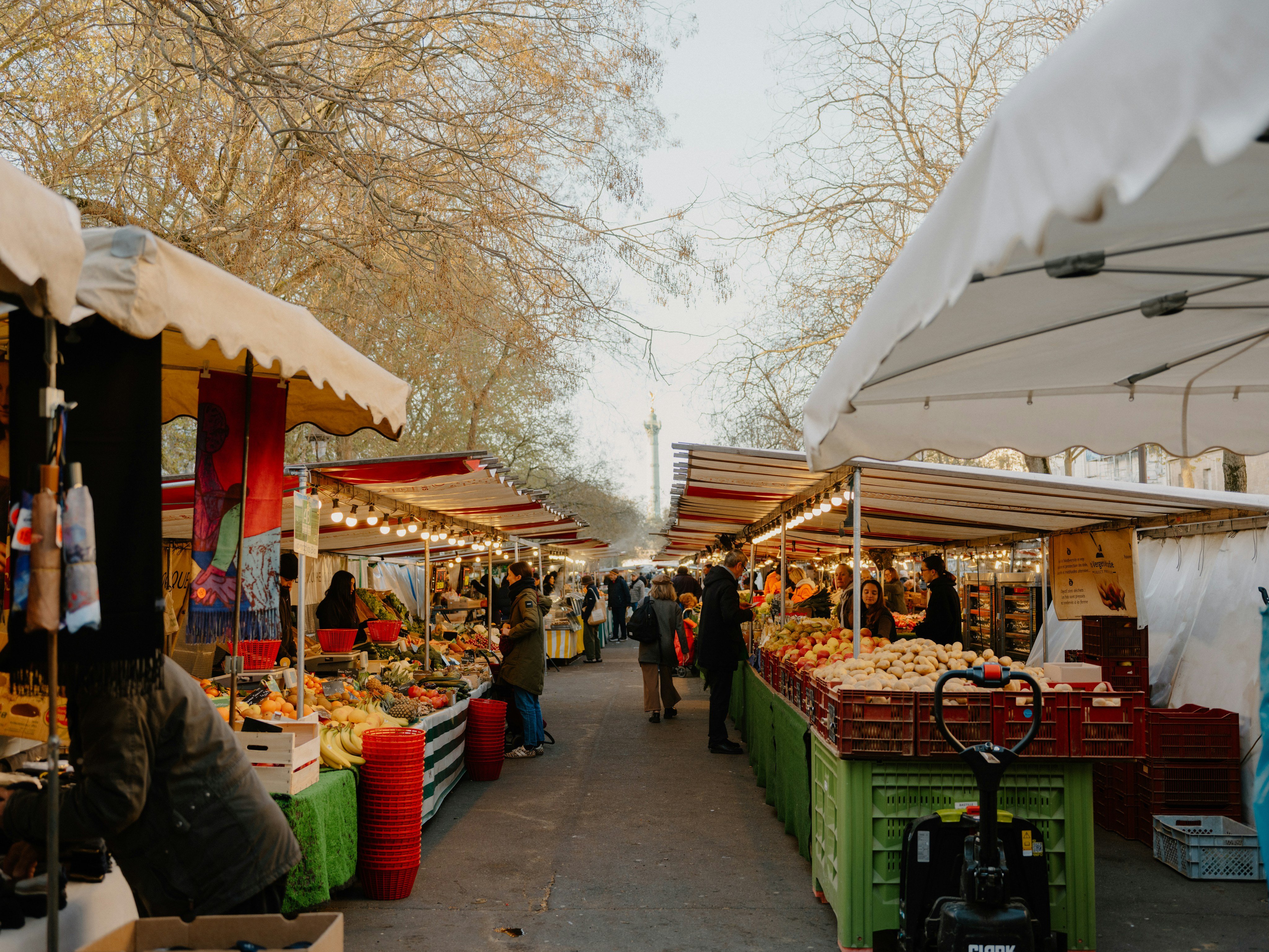 Outdoor market stalls lined with fresh produce under white canopies