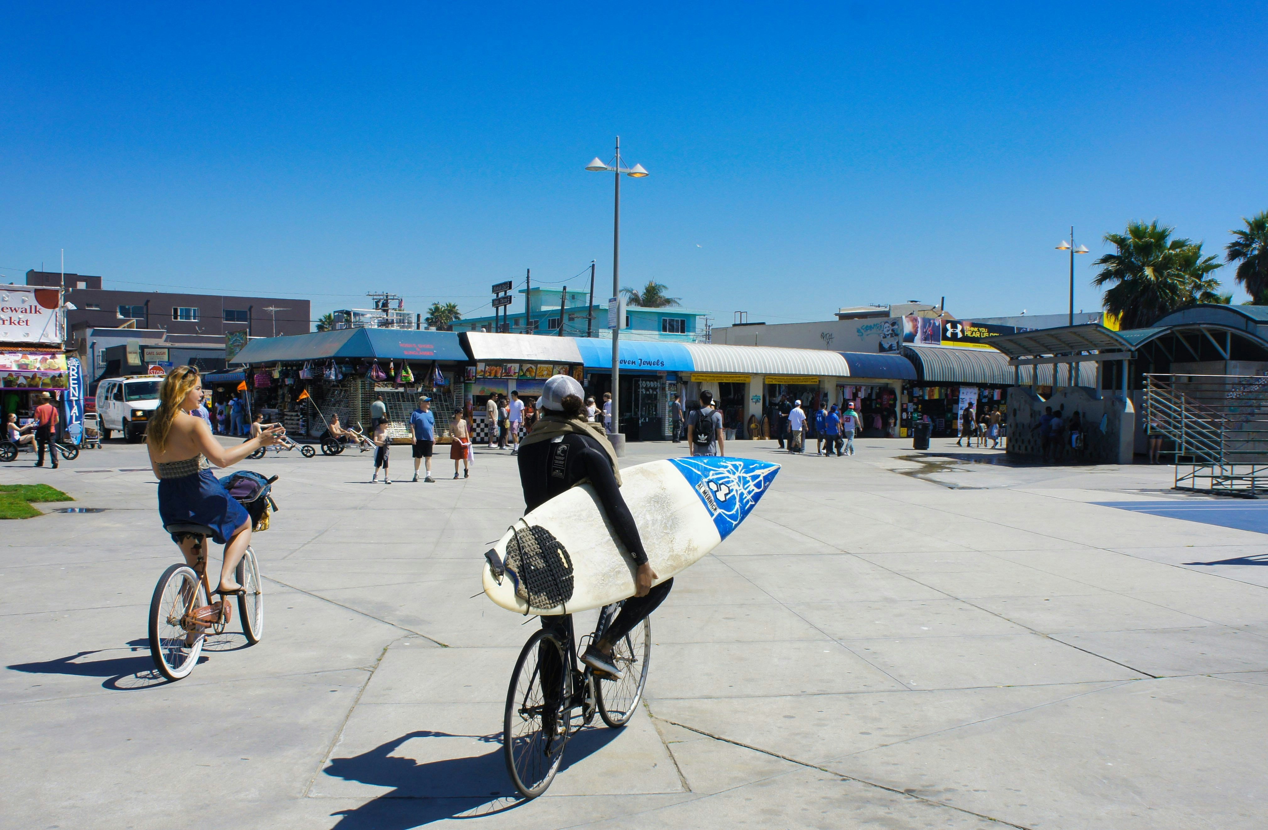 Cyclists on the Venice Beach boardwalk on a clear blue-sky day