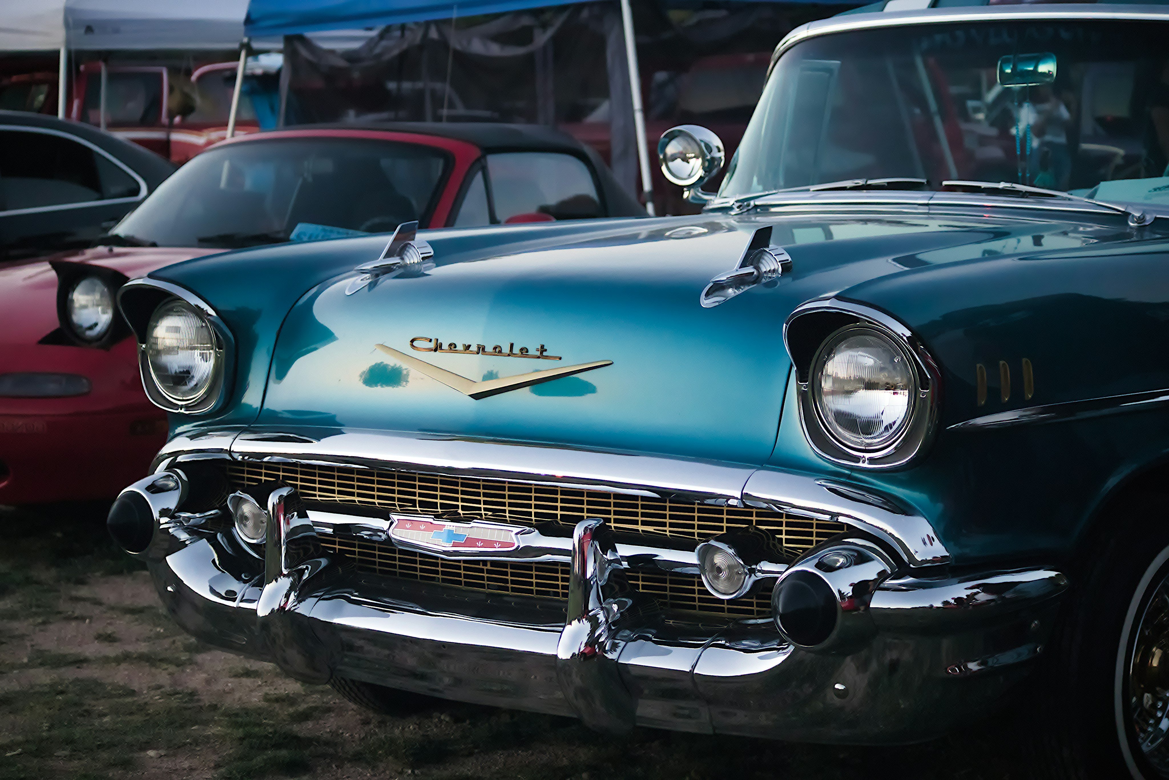A teal 1957 Chevy Bel Air at an outdoor classic car show