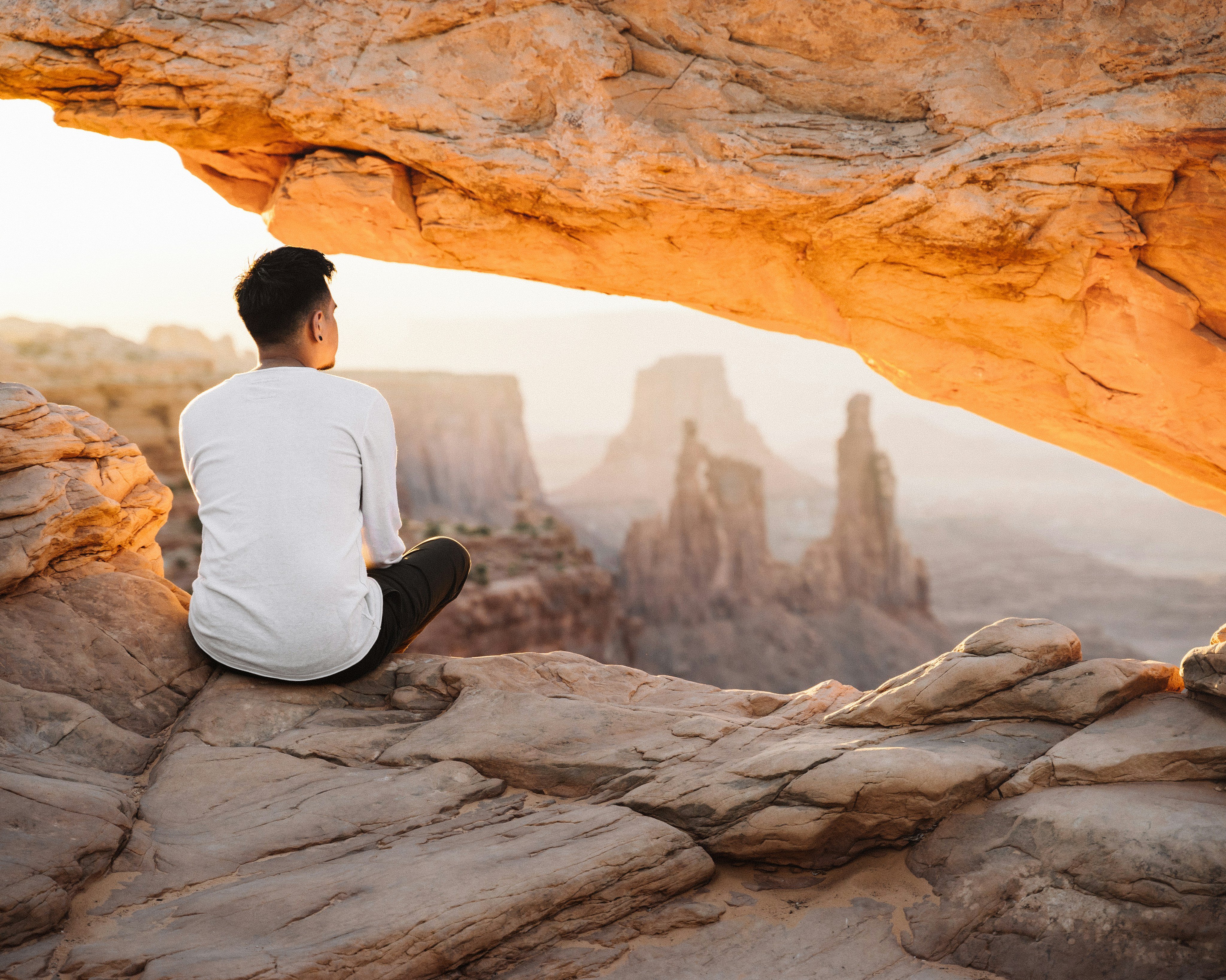 Man meditating in a canyon arch at sunrise