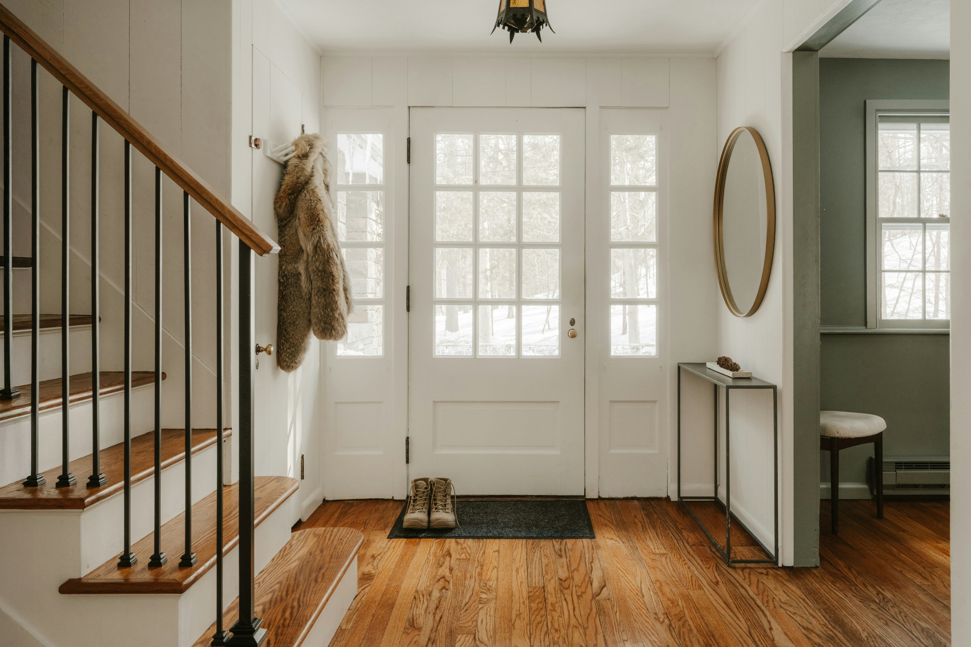 Bright welcoming foyer with white double doors and staircase