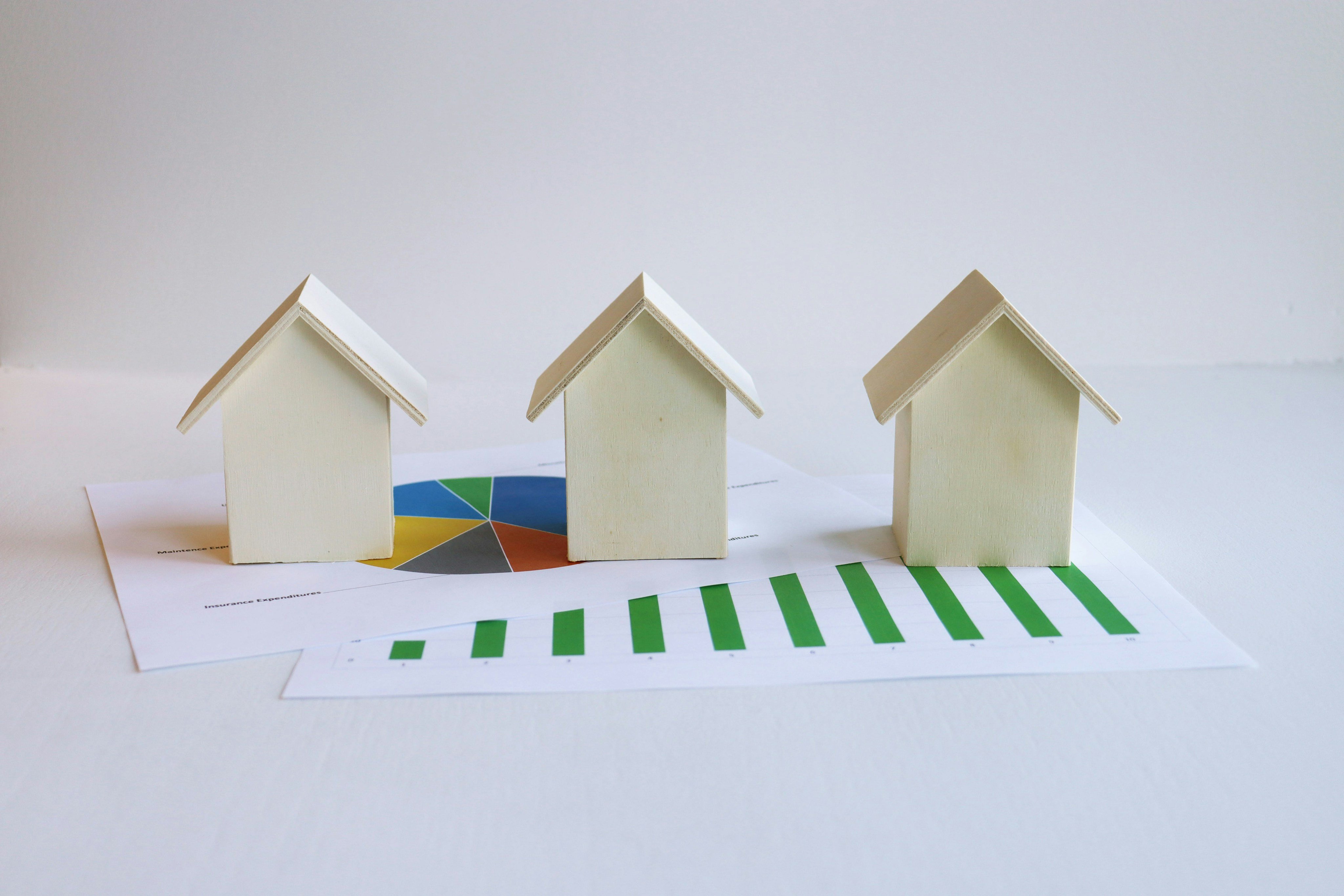 Three wooden house models on investment charts representing short term rental investing