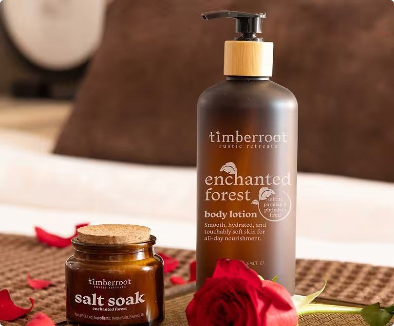 Timberroot Enchanted Forest body lotion and salt soak beside rose petals