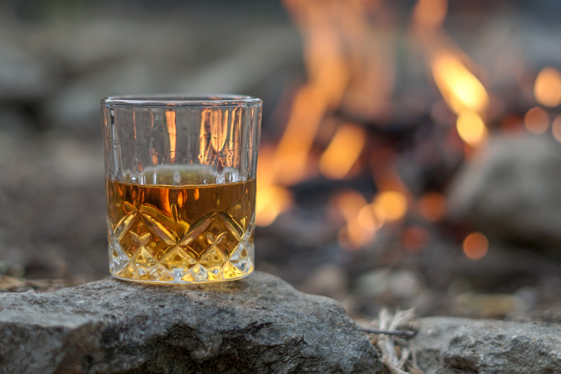 glass of whiskey by a campfire