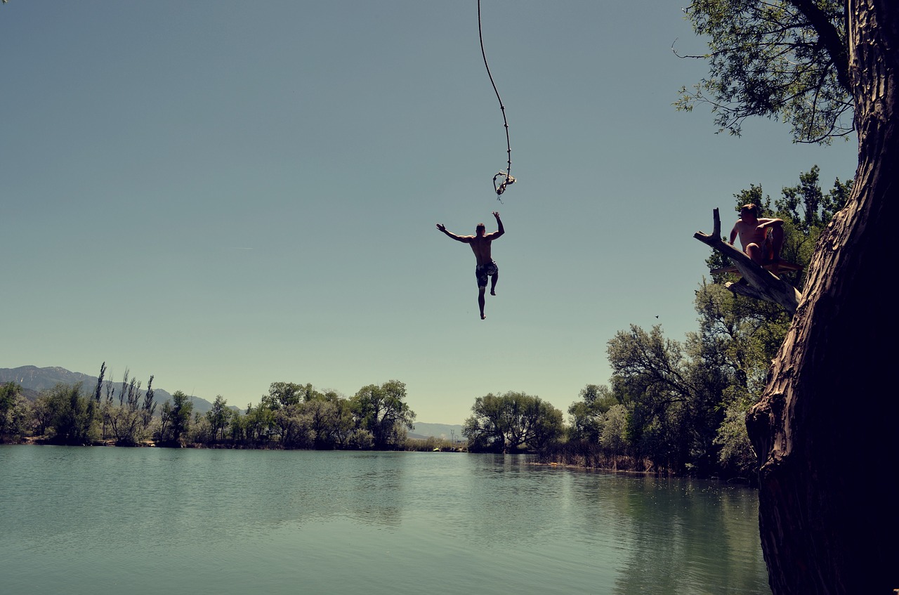 A man jumping from a tree into the lake