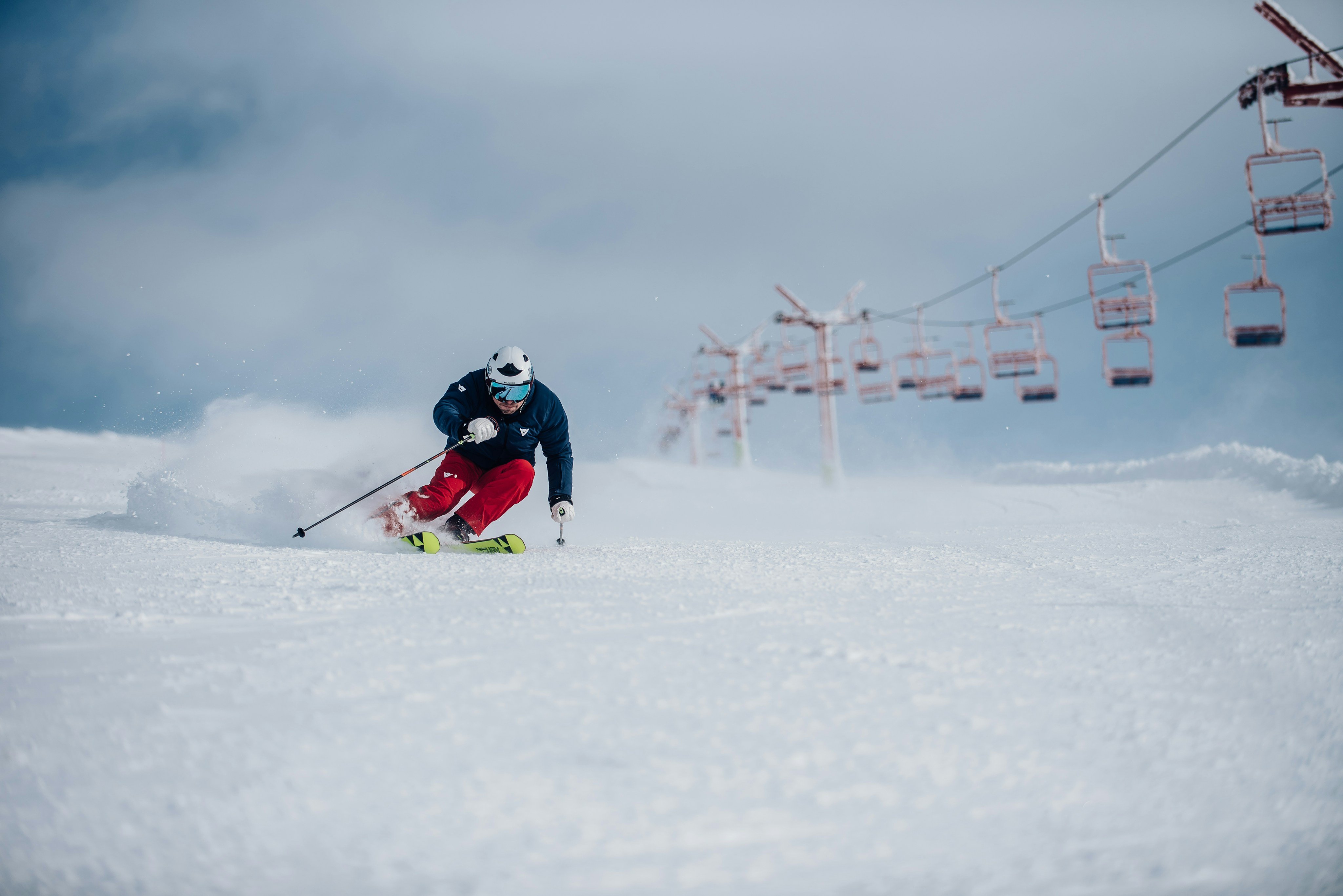 Skier carving down a slope under a chairlift