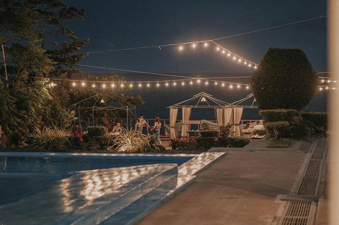 Outdoor string lights draped over a pool area at night
